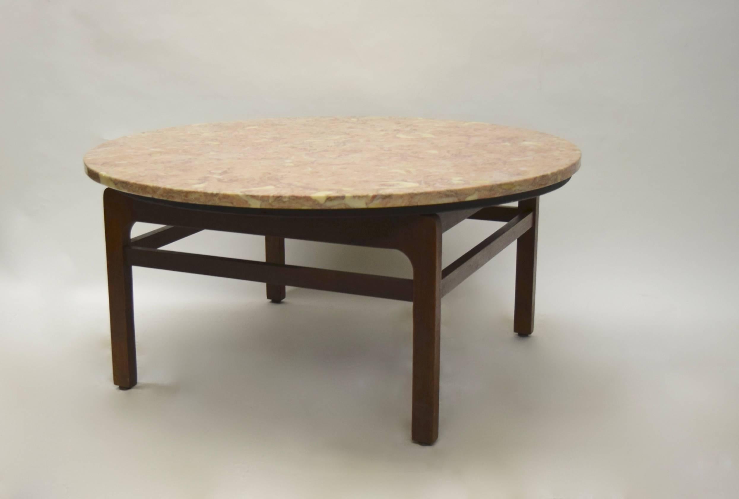 Coffee table by Jens Risoms has original labels underneath. The top is a 36 inch round 3/4 inch thick sealed piece of pink marble with flakes of lighter shades throughout sits on top of a walnut base thats 24 inches square with stretchers on all