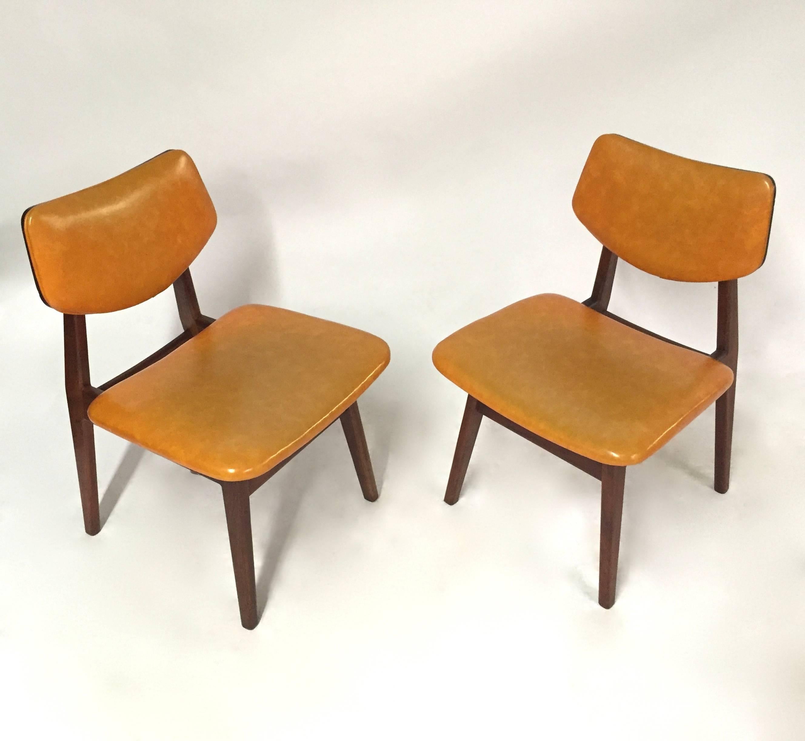 Pair of chairs by Jens Risom have angular walnut frames with floating tapered seat and back covered in original caramel vinyl.
