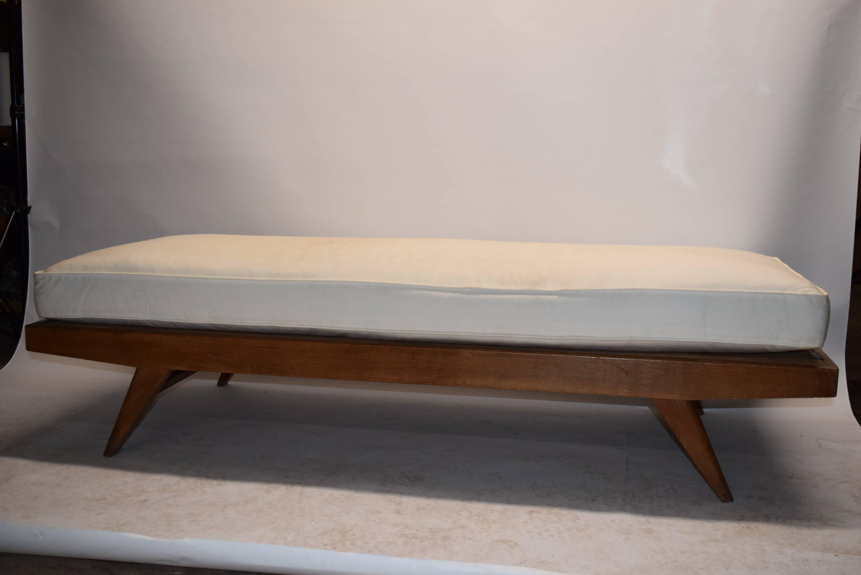 Daybed in oak with four angled tampered legs and a stretcher at each end. The cushion was recently made and upholstered in muslin.