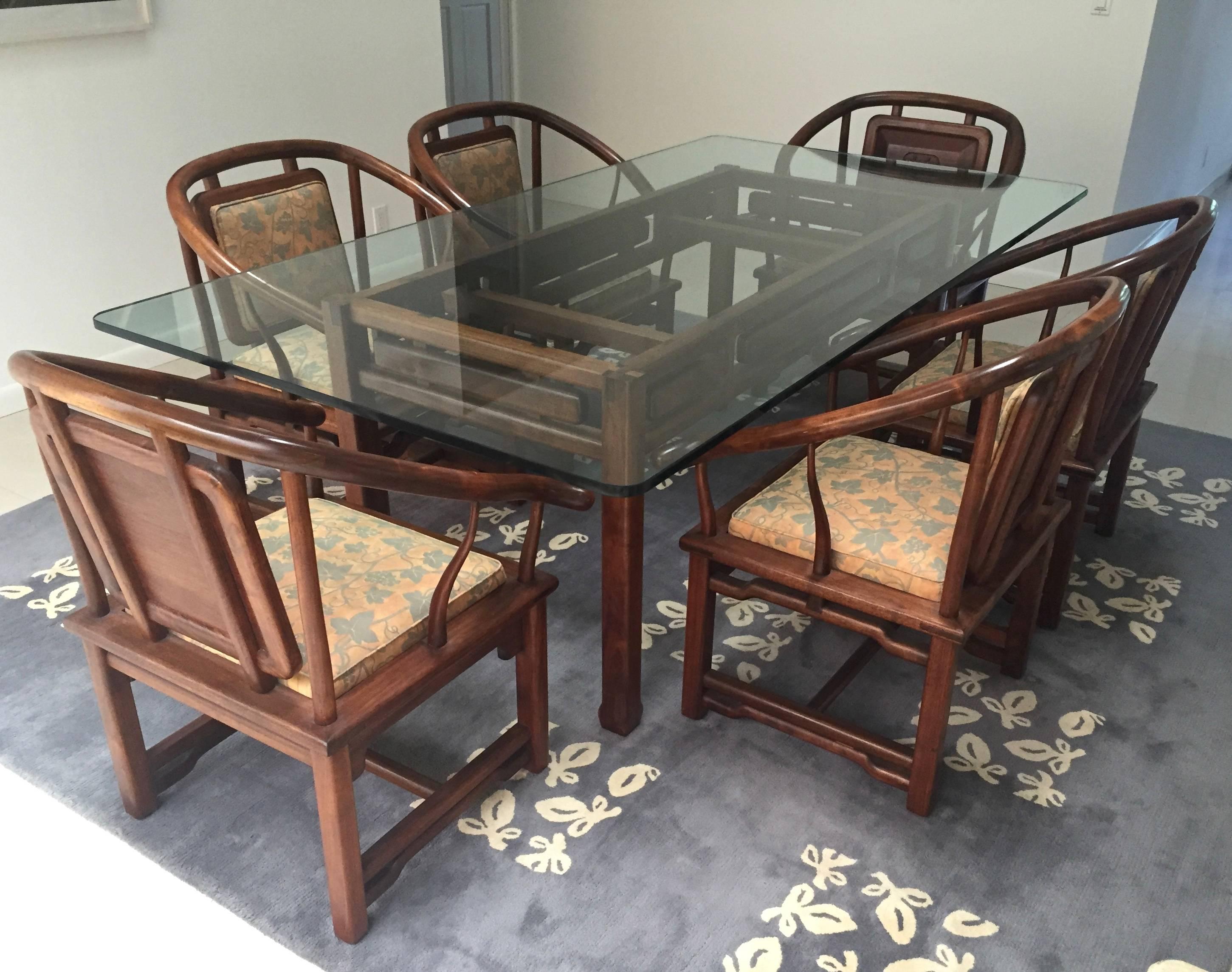 Ensemble de salle à manger en bois sculpté à la main, composé de six chaises avec coussins Fortuny et d'une base de table assortie qui supporte un plateau en verre transparent, le tout dans un motif asiatique. Les deux fauteuils de tête ont un