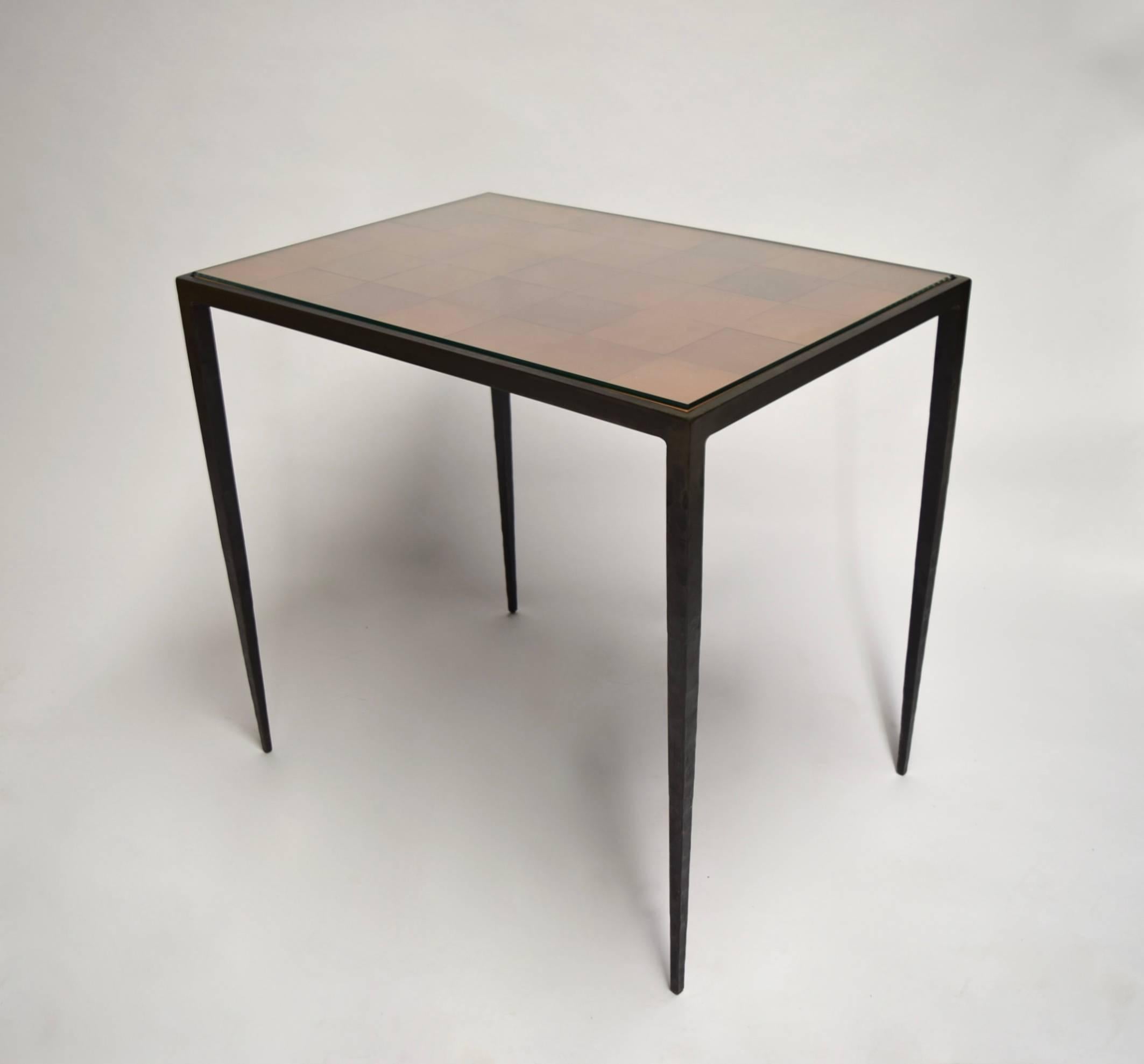 Occasional table in hammered, patinated bronze with tapering legs and an inset top comprising 35 square leather pieces. The protective clear glass top is shown in images 2-4.