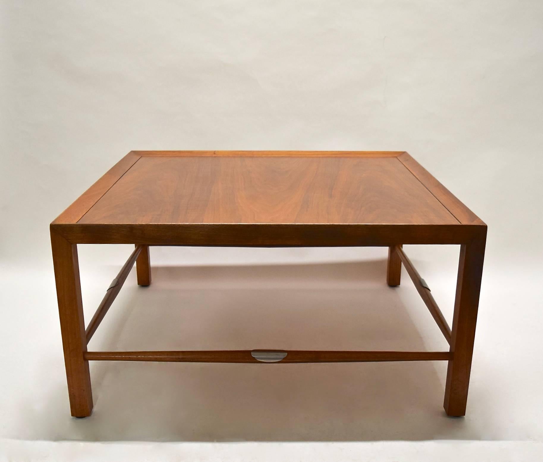 Walnut coffee table made by Heritage Henredon with four tapering wood stretchers that each have a curved metal detail in the center. The table has the original stampings on the underside of the top.