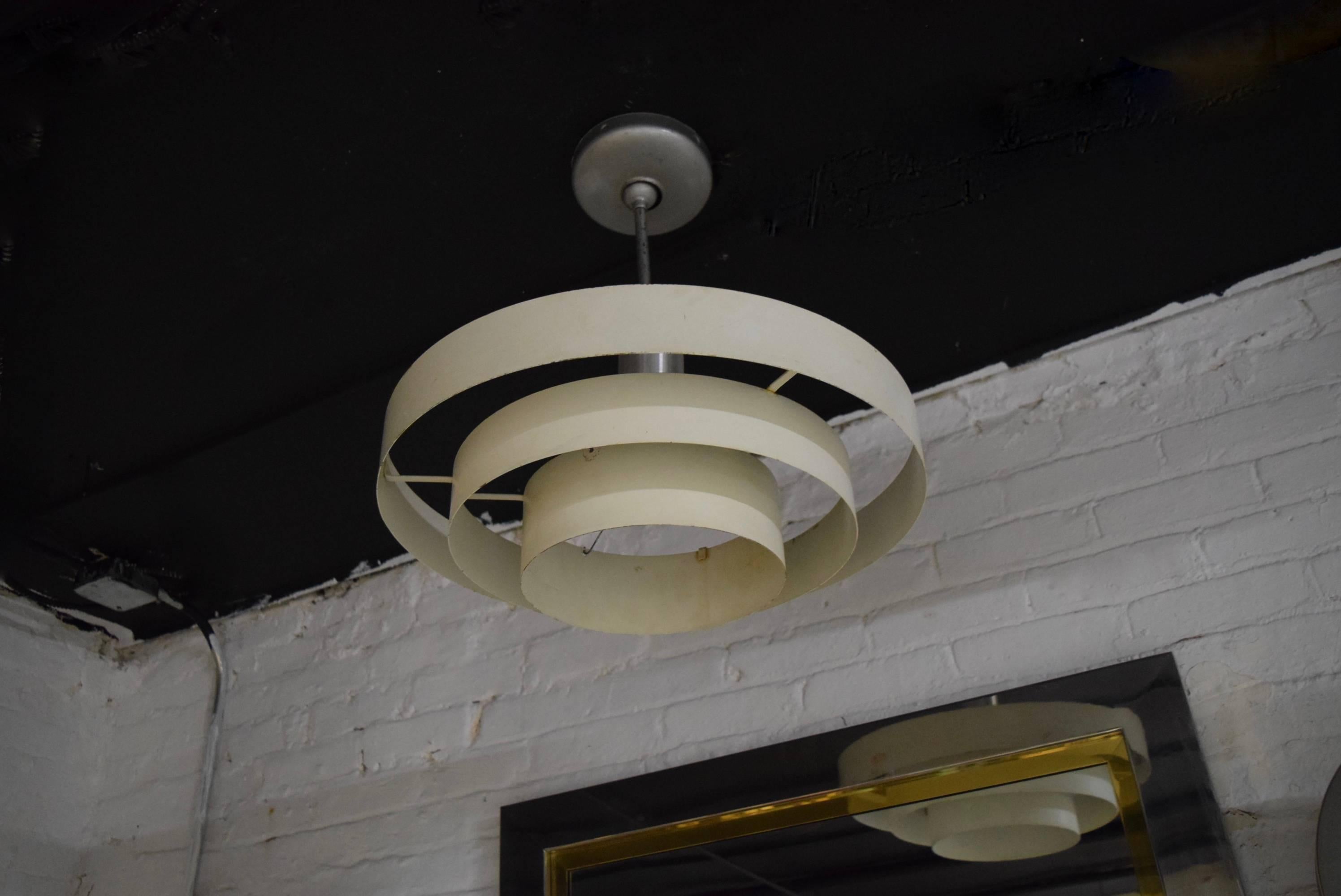 Ceiling fixture has a single centred standard socket with a stainless defuser surrounded by three rings of off-white enameled metal each graduating in size. The fixture has original stem and canopy.