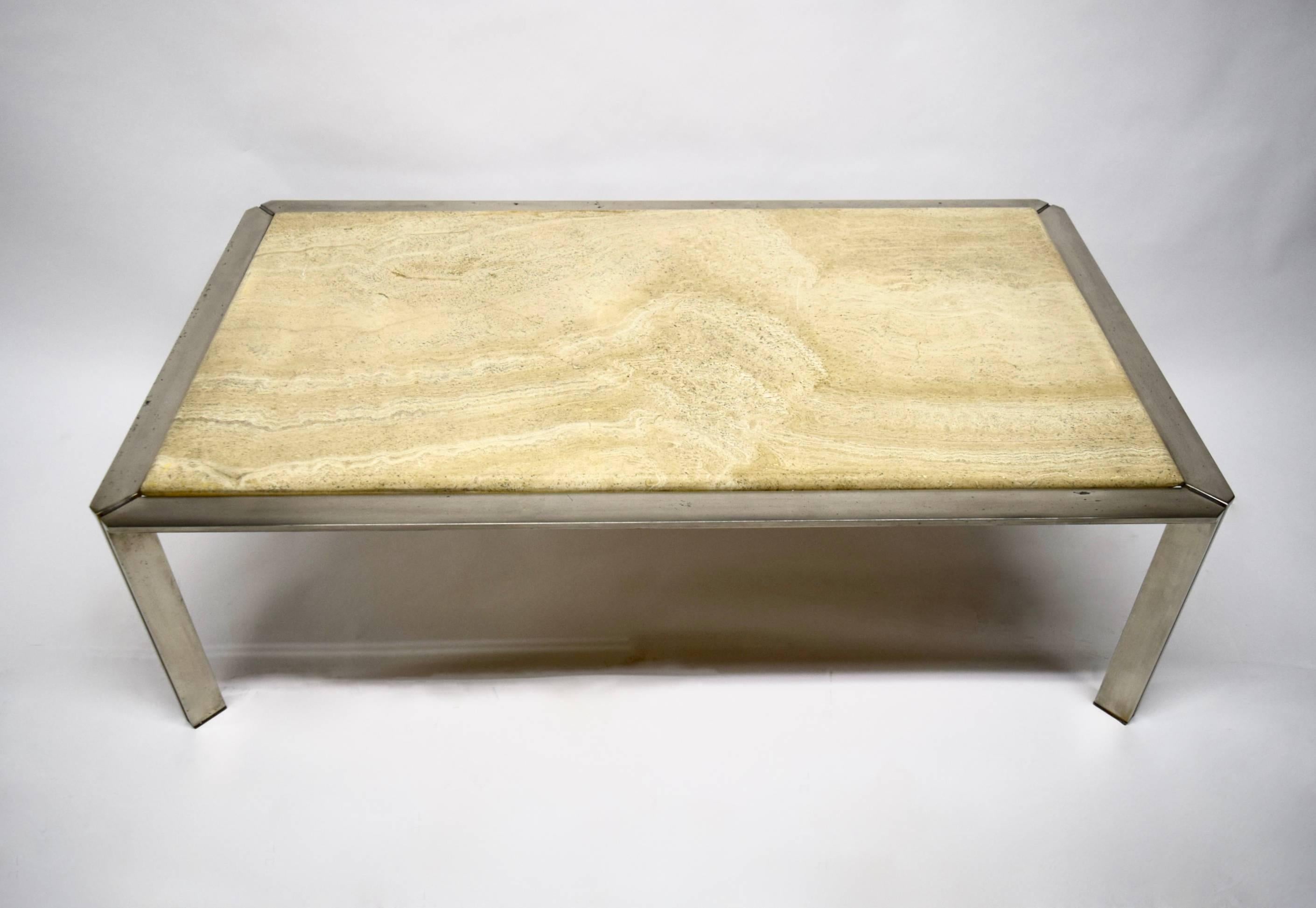 Coffee table has a nickel-plated solid steel base, each leg with linearly cut corners that form a T, and an inset finished travertine top with curved edges.