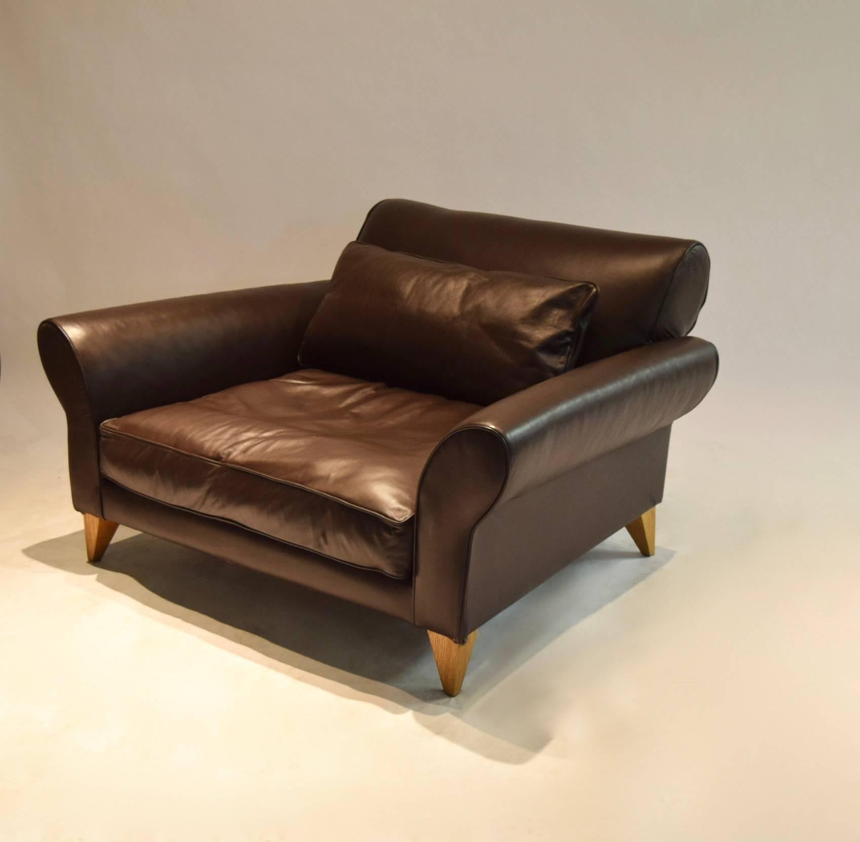 Very comfortable, extra wide “Ellipse” lounge chair by Terence Conran upholstered in chocolate brown leather with a seat cushion and a rectangular, loose back cushion in the same leather, curved back rest and arms, and supported on four angled,