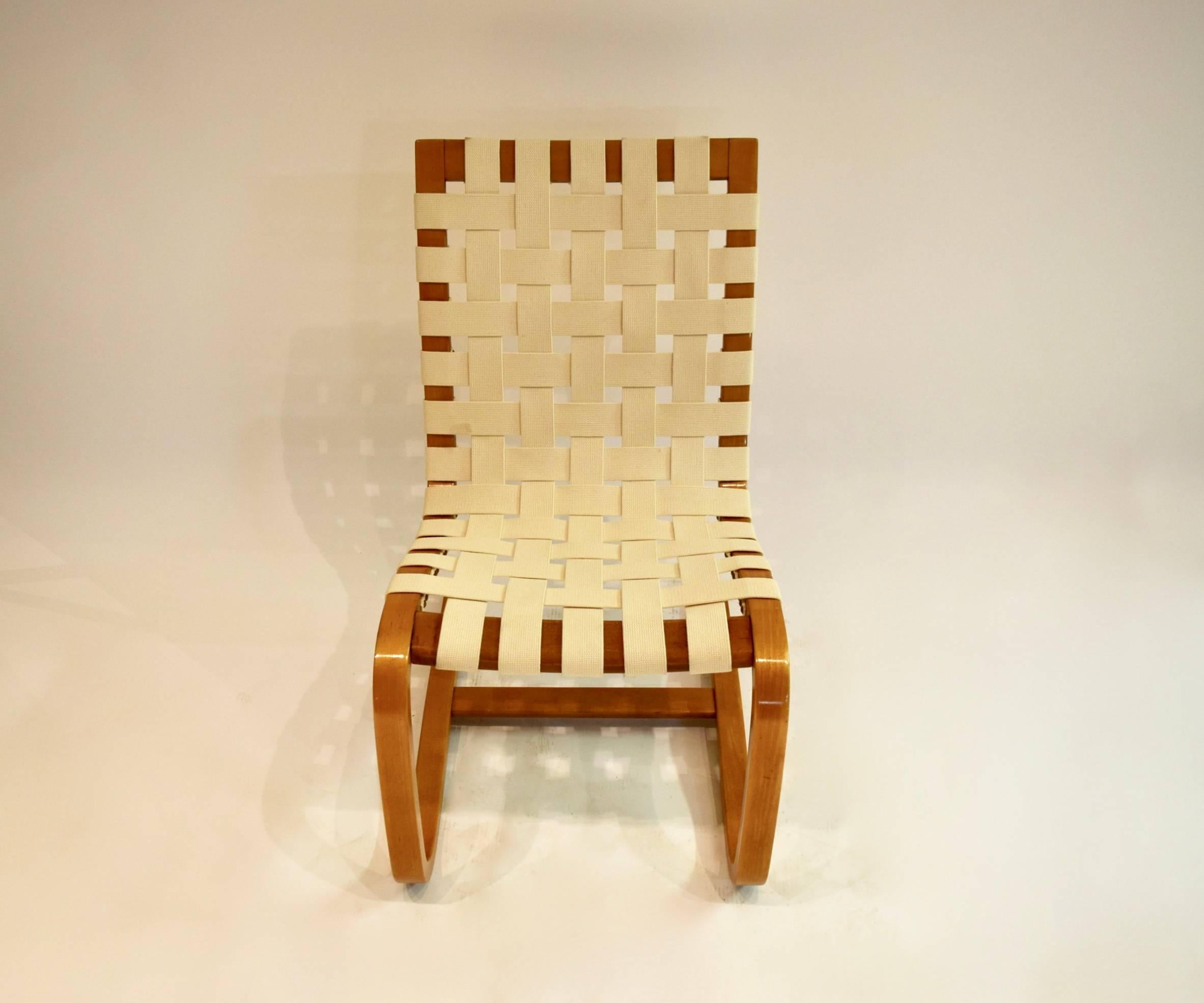 Pair of bentwood lounge chairs with off-white, woven fabric straps secured in by brass nailheads, and a supportive stretcher between the sled base legs.
 