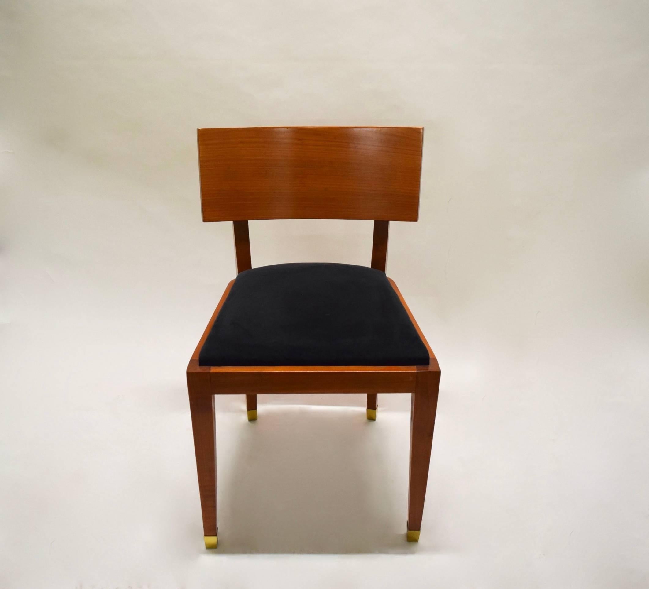 Four armless dining chairs in fruitwood with a curved backrest, tapered legs, solid brass sabots, and the seat cushion upholstered in black micro suede that was recovered in the early 2000s.
The dining table is also available.