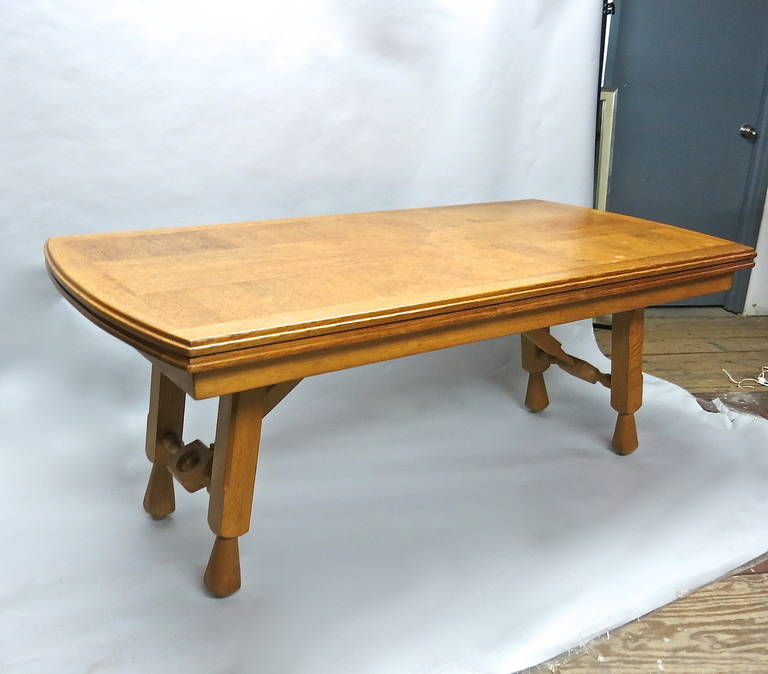 Strong dining table with a detailed oak top that has hand-carved, rounded and routed edges on all sides and two leaves that slide underneath the top. Each end of the top and the two leaves are arched; this creates a smooth continuation in wood grain