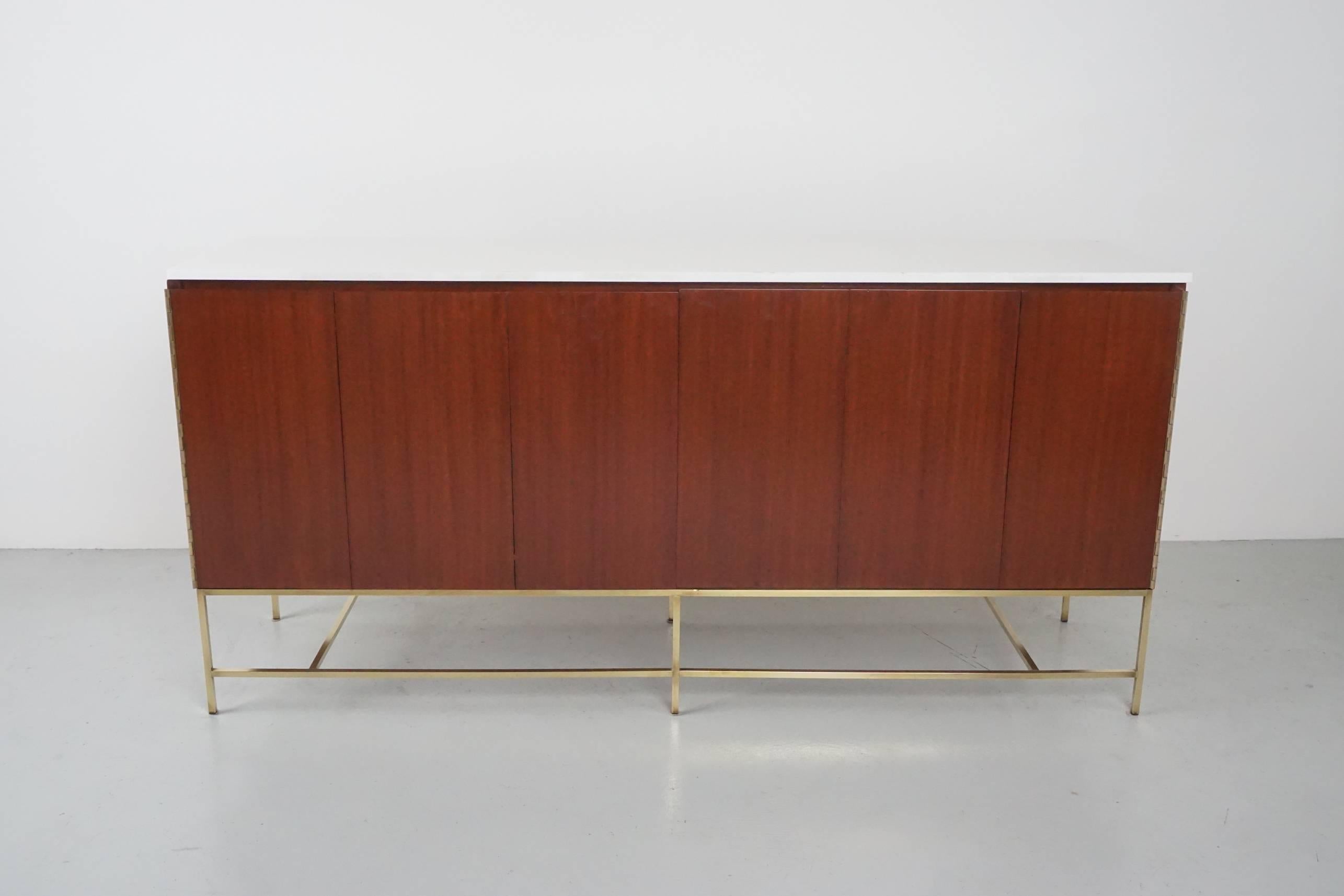 Gorgeous Paul McCobb credenza for Calvin featuring two bi-folding doors with ample storage on both sides consisting of four drawers and storage. Signed with original manufacturer's label. Beautiful original solid milk glass piece top and newly