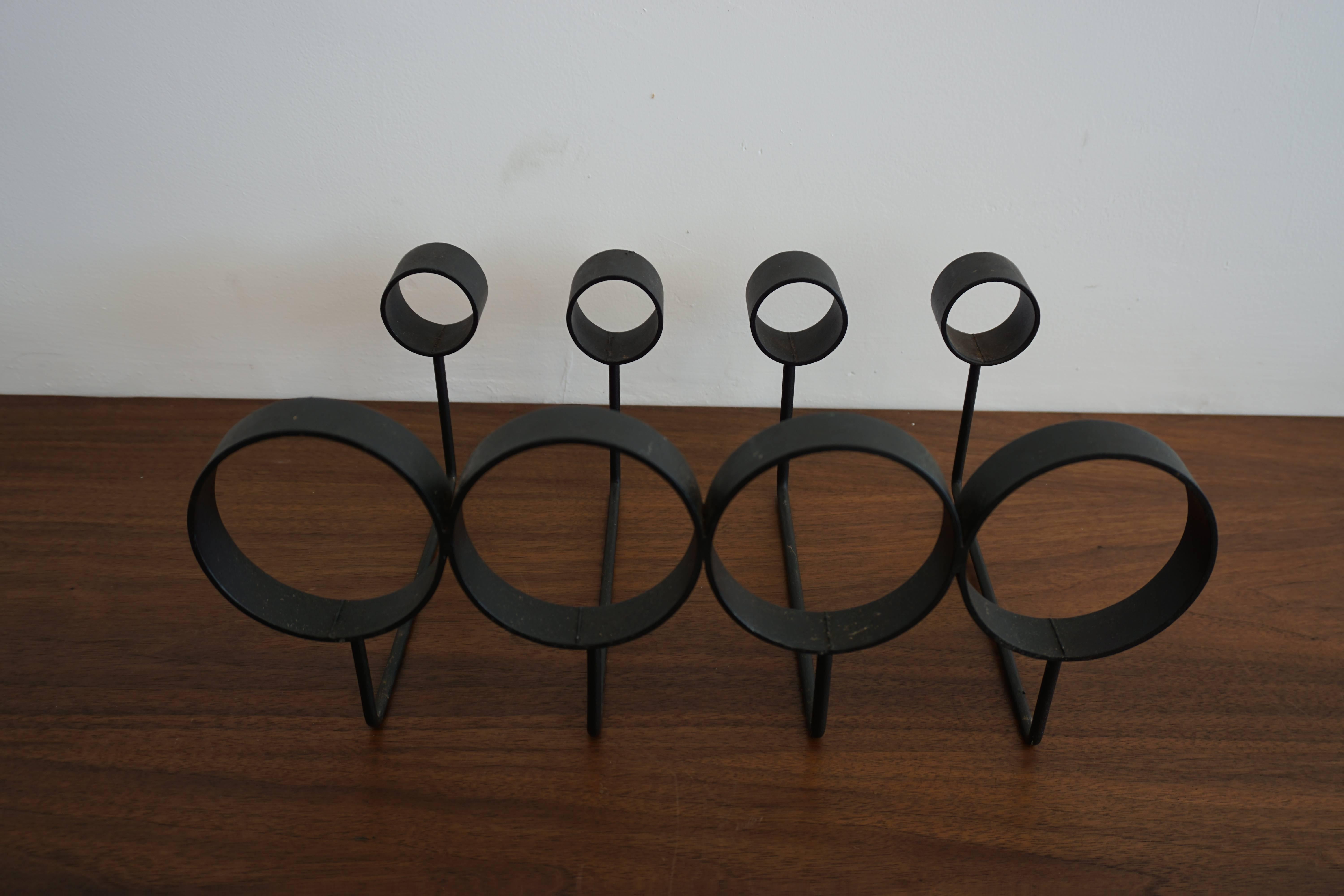 Simple iron modernist wine rack. 

Holds four bottles horizontally.