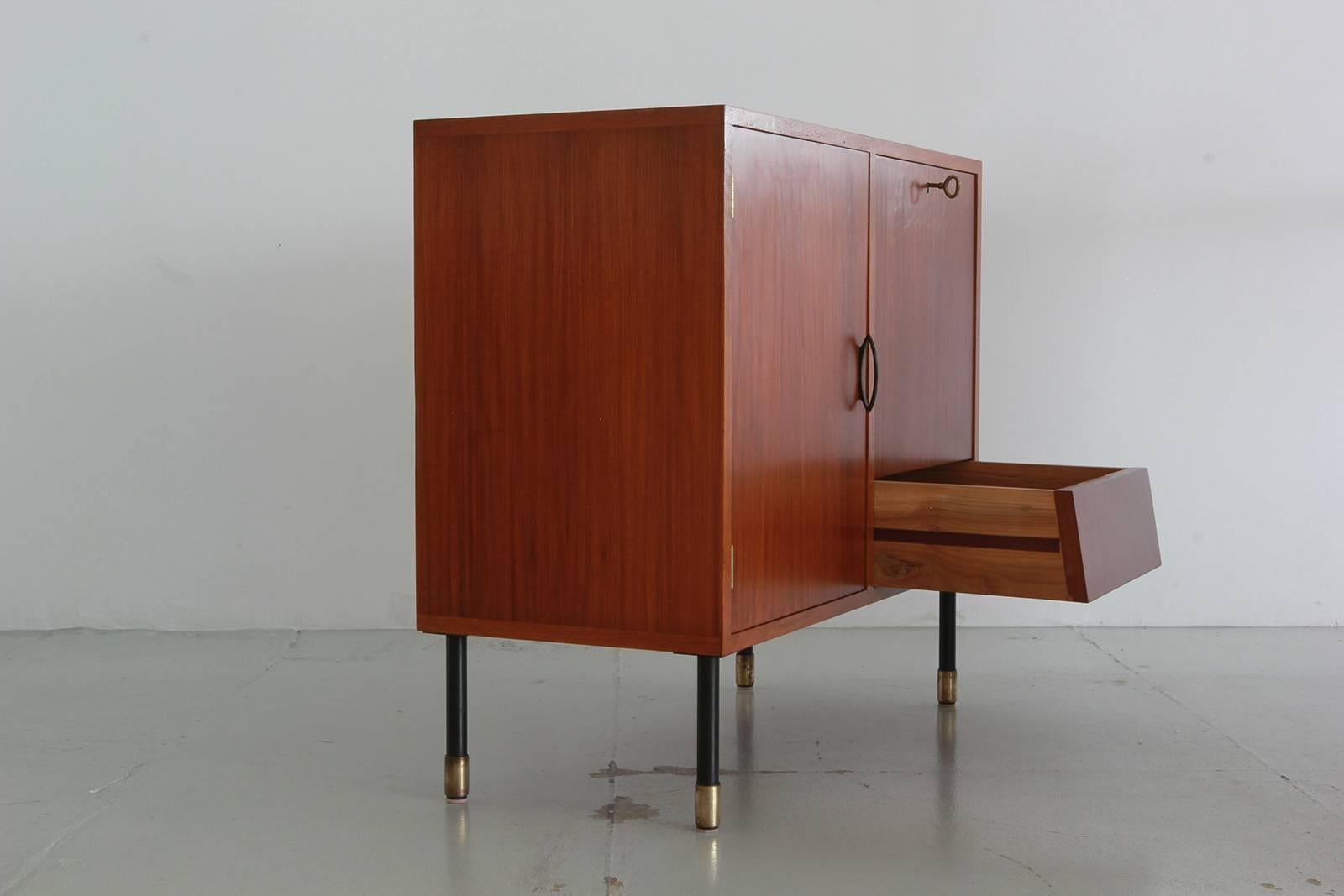Handsome Italian cabinet by I.S.A Bergamo with open cabinet shelving, drop down door with open shelving, and a single drawer. Brass hardware on iron legs and brass feet.
Total of three similar cabinets available.
