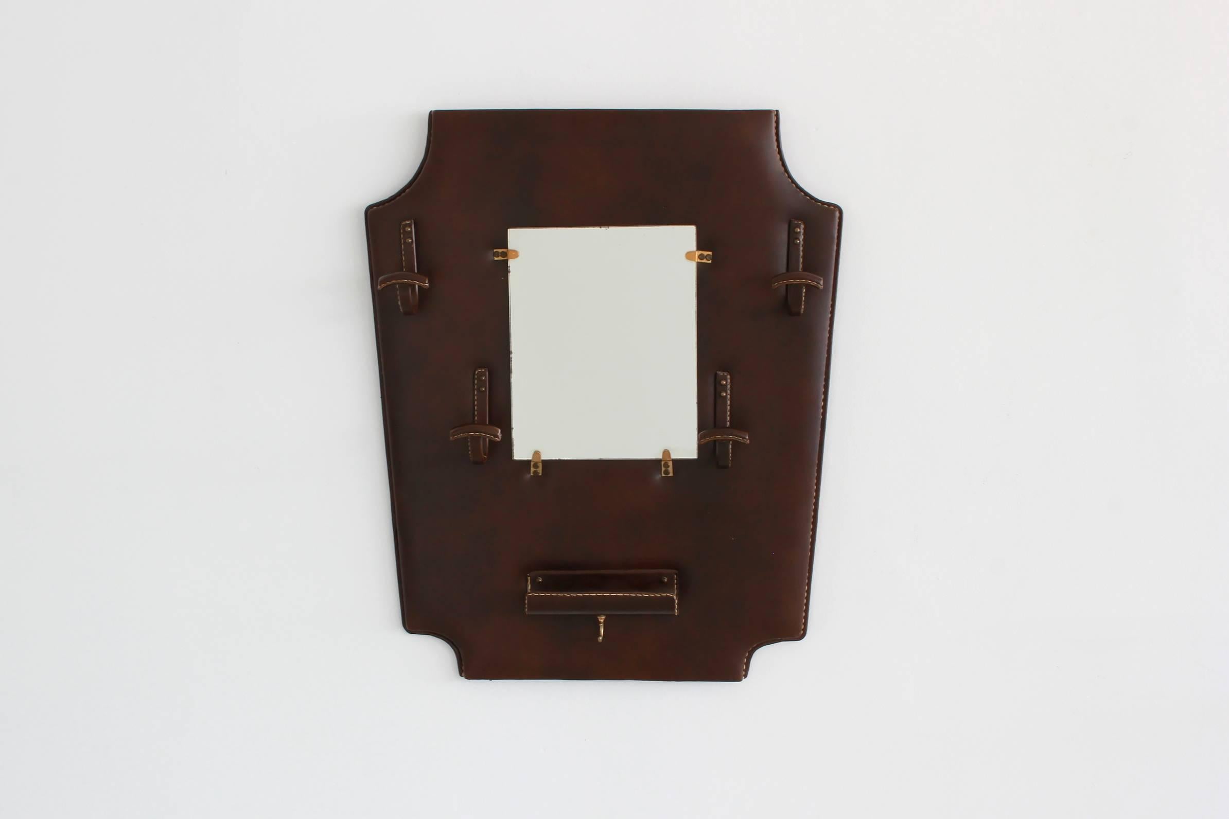 Jacques Adnet chocolate brown wall mirror with hooks and catch all with brass hardware, contrast stitching and equestrian style shape.

 