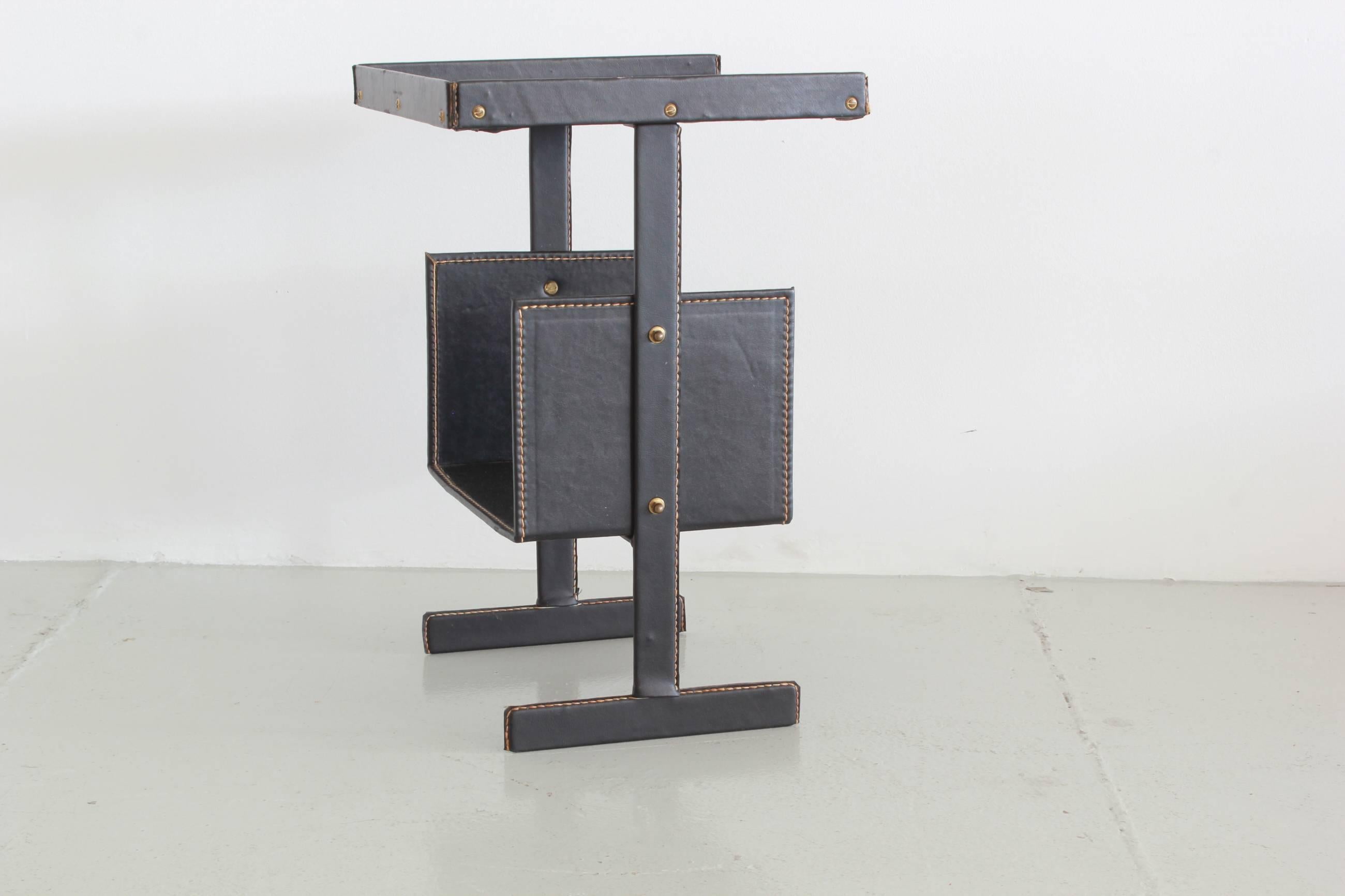 Leather wrapped side table with brass hardware and contrast saddle stitching by French designer Jacques Adnet. This table was originally designed as a telephone table, but works great as a side table next to a chair or sofa with a shelf for storage.