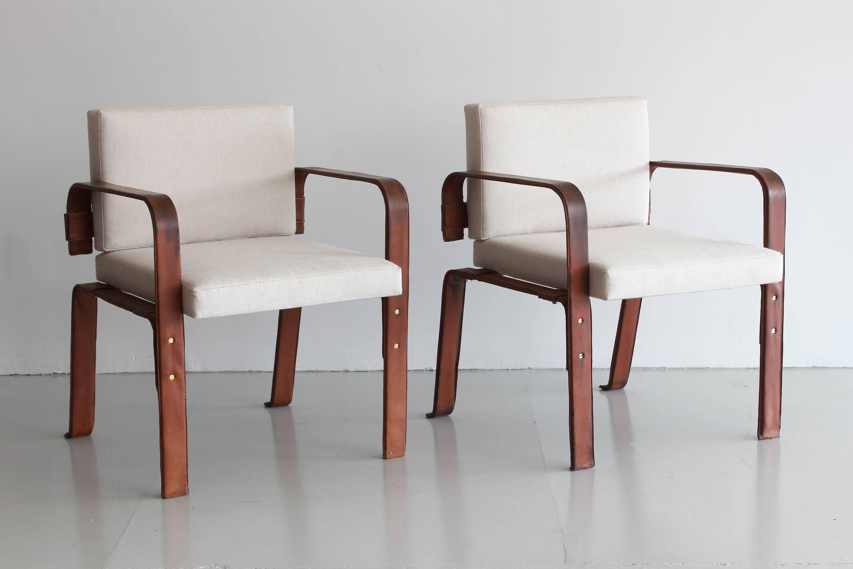 Pair of accent chairs in heavy gauge bent metal wrapped in leather with perfect distress and patina. Newly reupholstered in Classic linen. Superb quality and details with exposed screws and beautiful saddle leather.