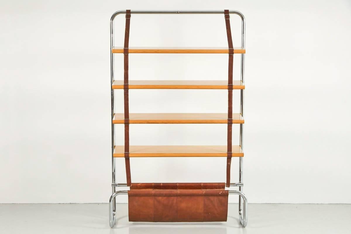 Impressive large-scale Italian wall shelf designed by Luigi Massoni for Poltrona Frau, 1971. Chromed tubular steel frame with natural wood shelves suspended by brown leather straps. Gorgeous brown saddle leather catch all at base - perfect for