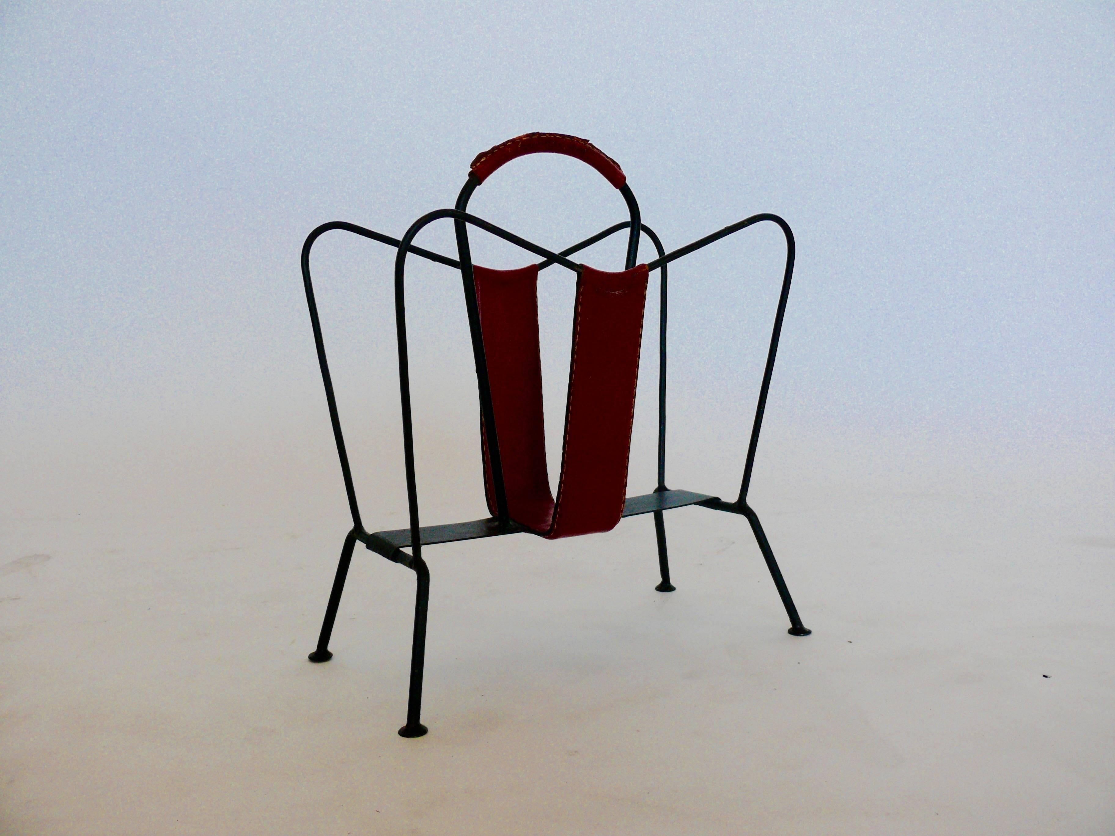 Handsome magazine rack by Jacques Adnet in aged iron and red leather with contrast stitching. Very good vintage condition.