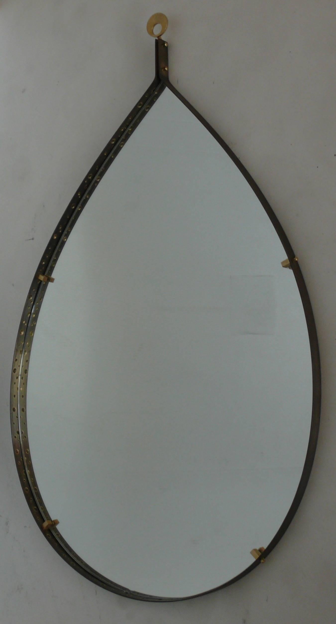 Italian brass floating mirror in tear drop shape. Unique handmade perforated detailing inside brass trim with mirror floating by brass square hardware.