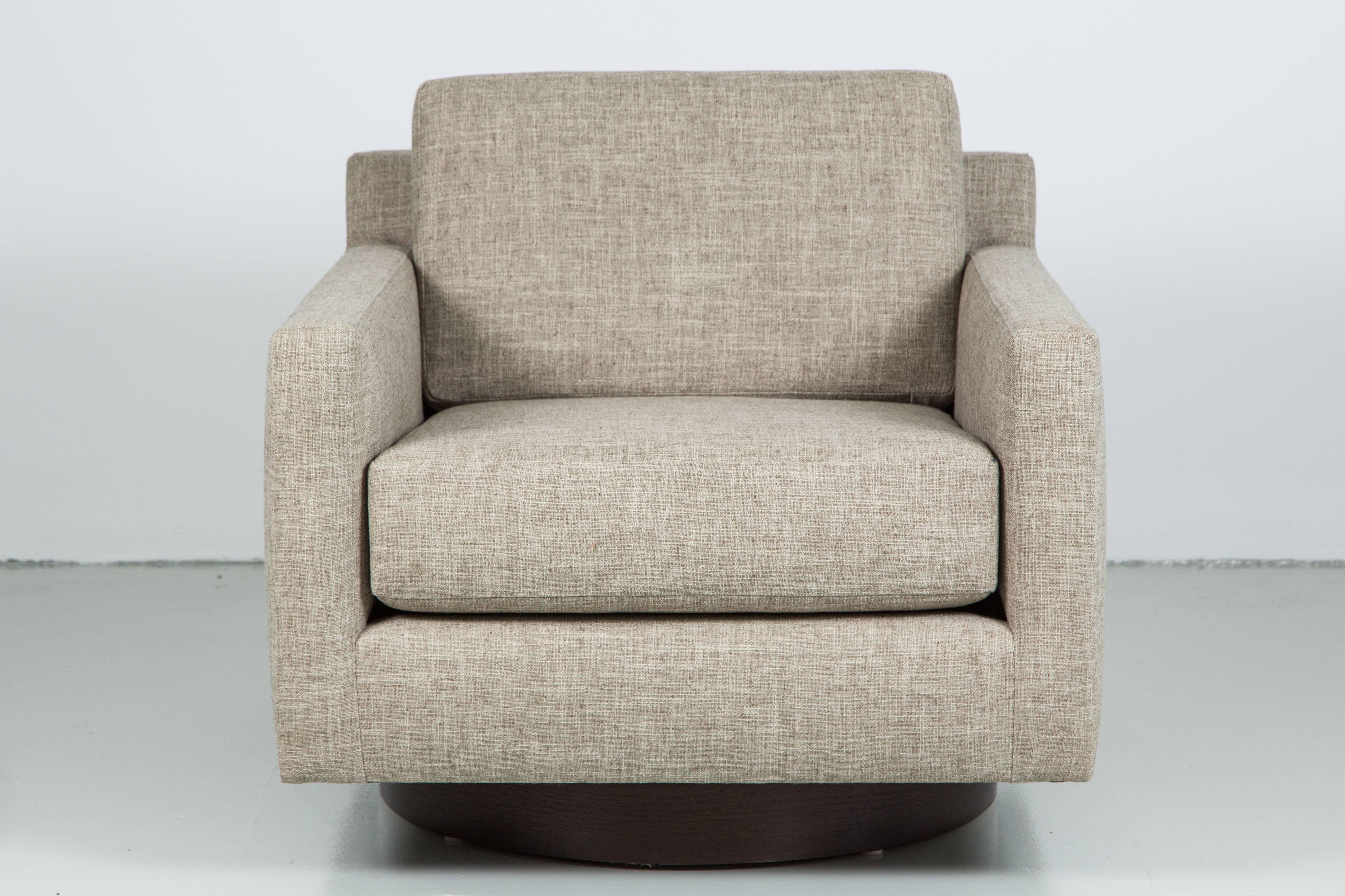 Fantastic pair of newly produced square swivel chairs in the style of Milo Baughman. Comfortable cushioned seats with low profile back cushion. Sits on walnut wood swivel base. 
Shown upholstered in a soft linen. 
Great modern design with sleek