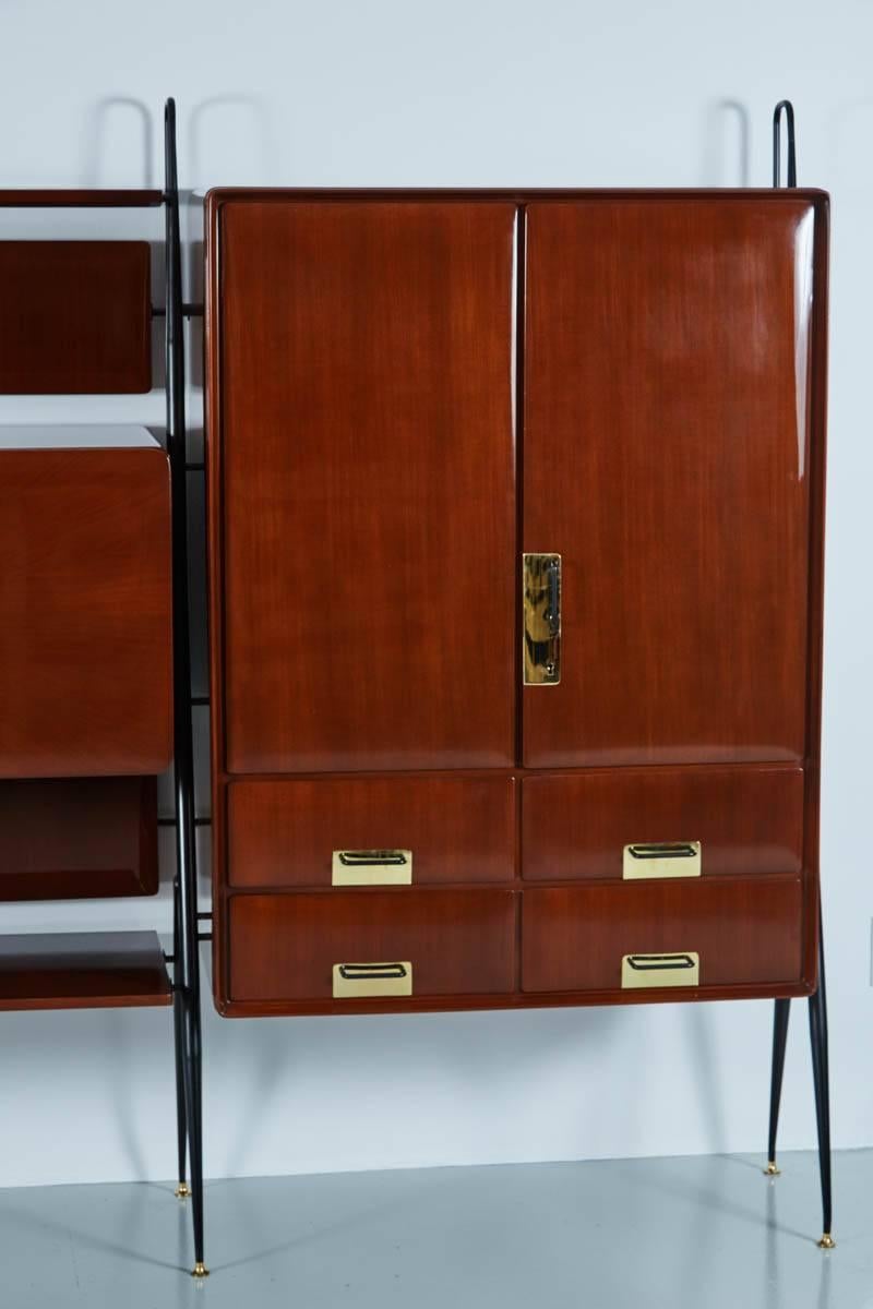 Handsome Italian free standing wall unit by Silvio Cavatorta featuring two cabinets, four drawers and a pull down mirrored bar. Newly refinished in a deep mahogany French polish. Polished brass hardware floating on elegant black legs.
