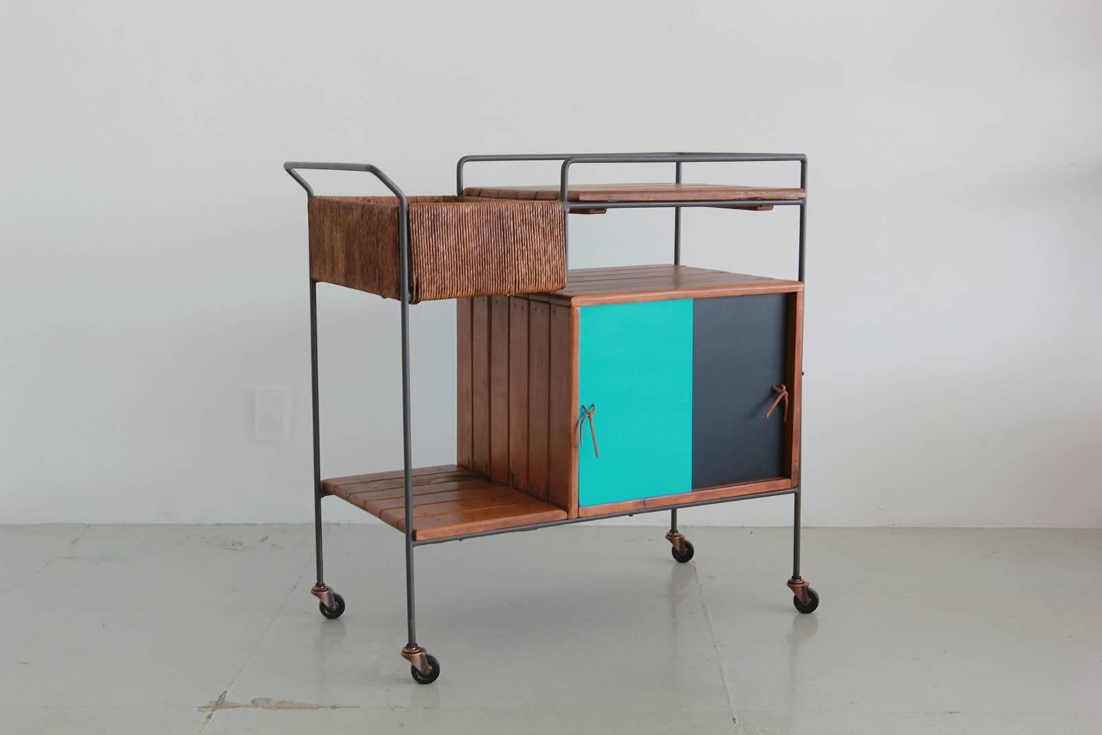 Great bar cart by Arthur Umanoff for Raymor. Black wrought iron frame, wood slat shelving, woven rushed storage compartment and sliding lacquered doors with extra storage.