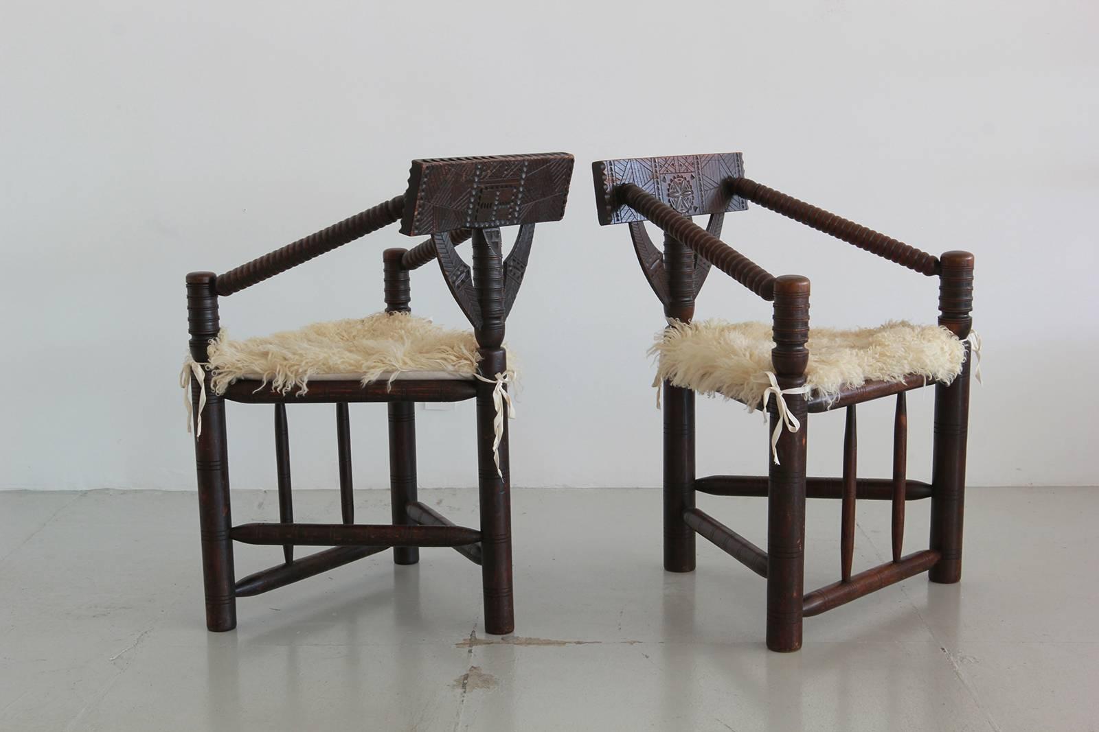 Wonderful pair of solid oak Monk chairs from Sweden carved with Native style detailing. Original long hair Mongolian sheepskin seat cushions.