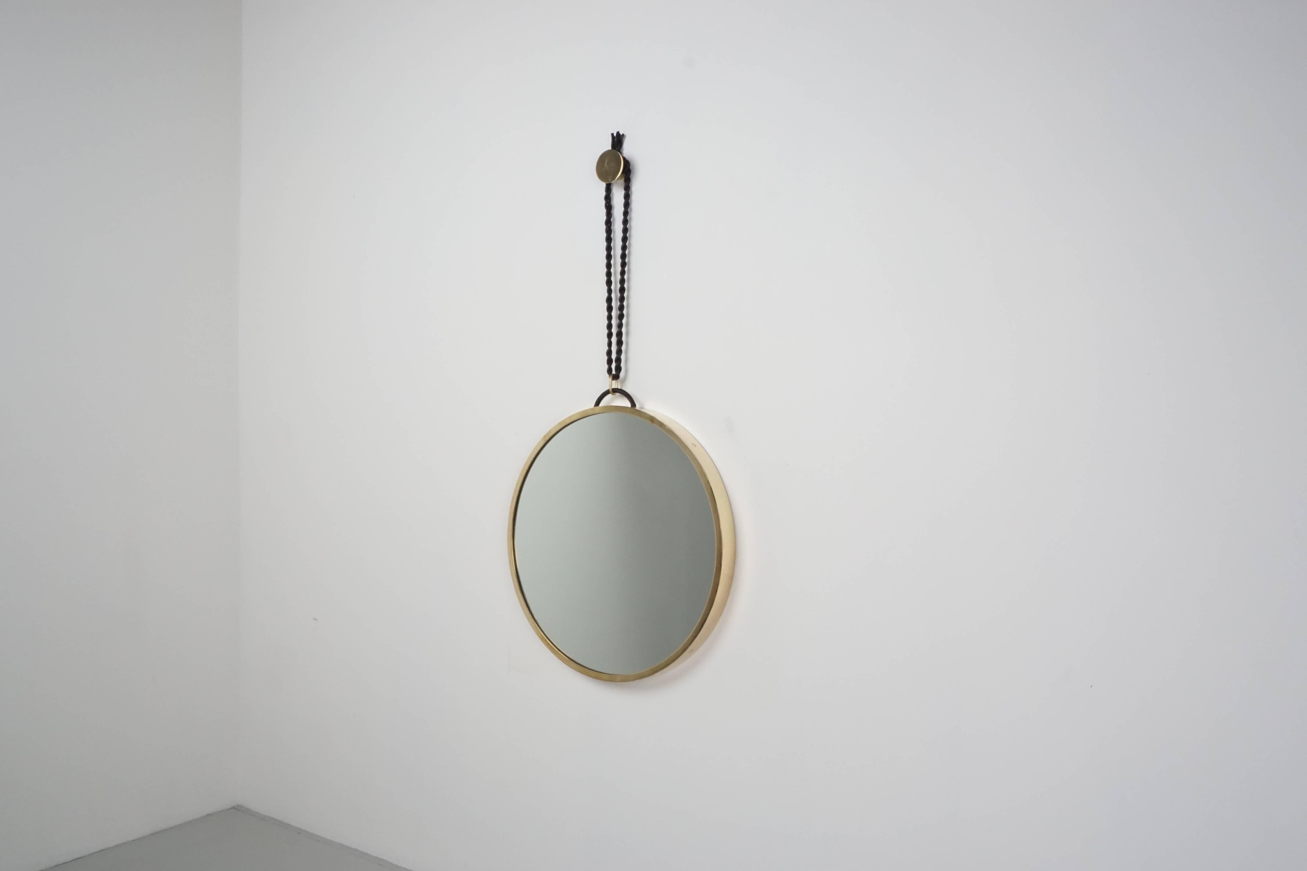 Stunning large mirror encased in polished brass frame designed by Orange. Braided black leather attached to mirror which hangs on a  coordinating round brass disc. Simply magnificent. Multiple available and can be made in custom sizes. 

24