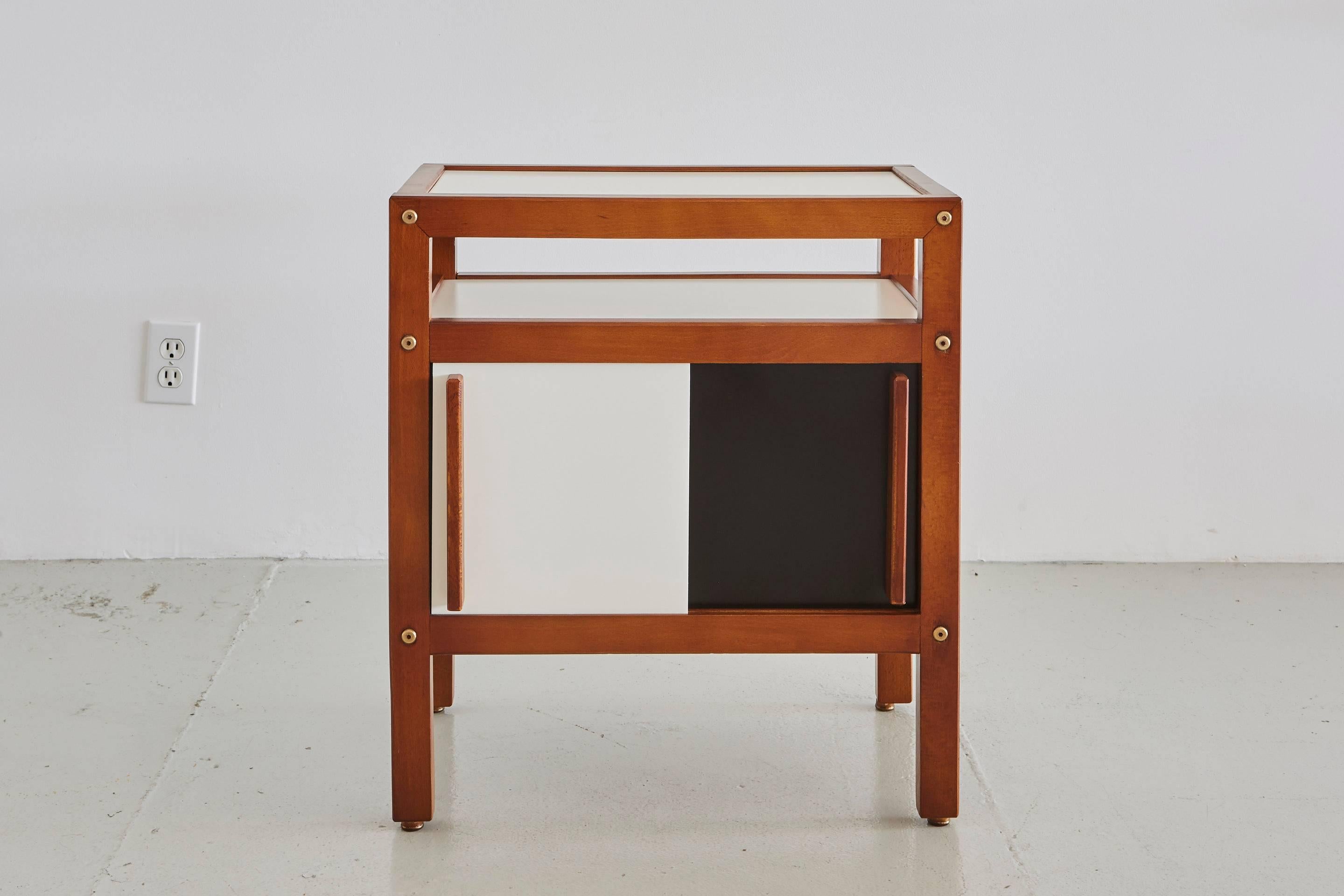 Pair of Andre Sornay end tables produced in 1950s, France. 
Constructed of teak wood, contrasting black and white sliding doors open to reveal storage and extra shelf. Great wood handle detail.