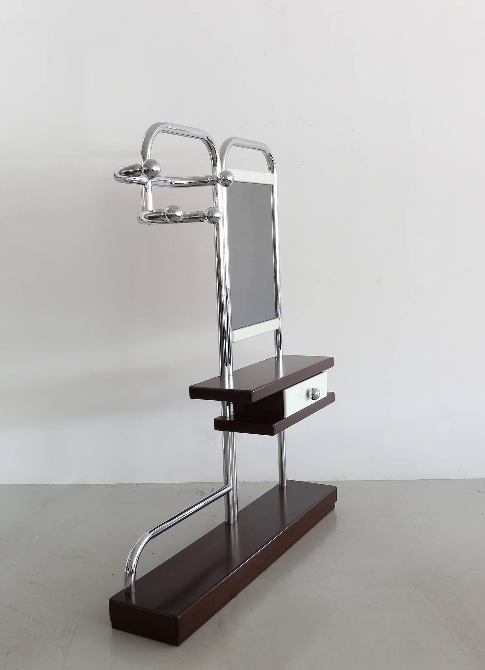 Unique vintage hall tree or valet with oversized tubular chrome frame in a Bauhaus style. Features a four hook coat rack and slightly tinted mirror. Handsome wood base and drawer with large chrome ball drawer pull to match the ball coat hooks. This