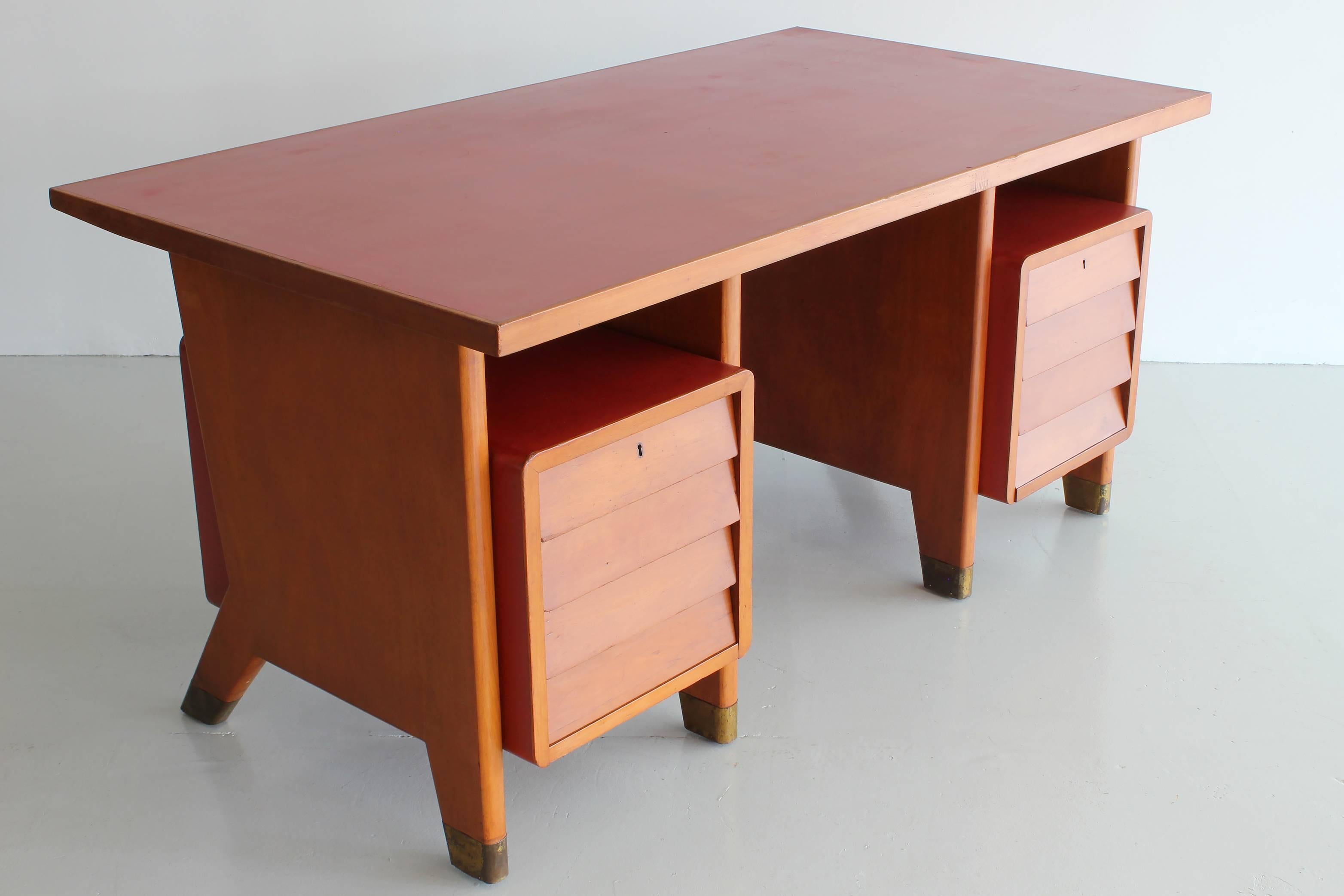 Gio Ponti designed desk for city offices of Forli, Italy. Original red linoleum writing surface with same linoleum wrapping the floating drawers. Brass sabots on the signature Gio Ponti leg.