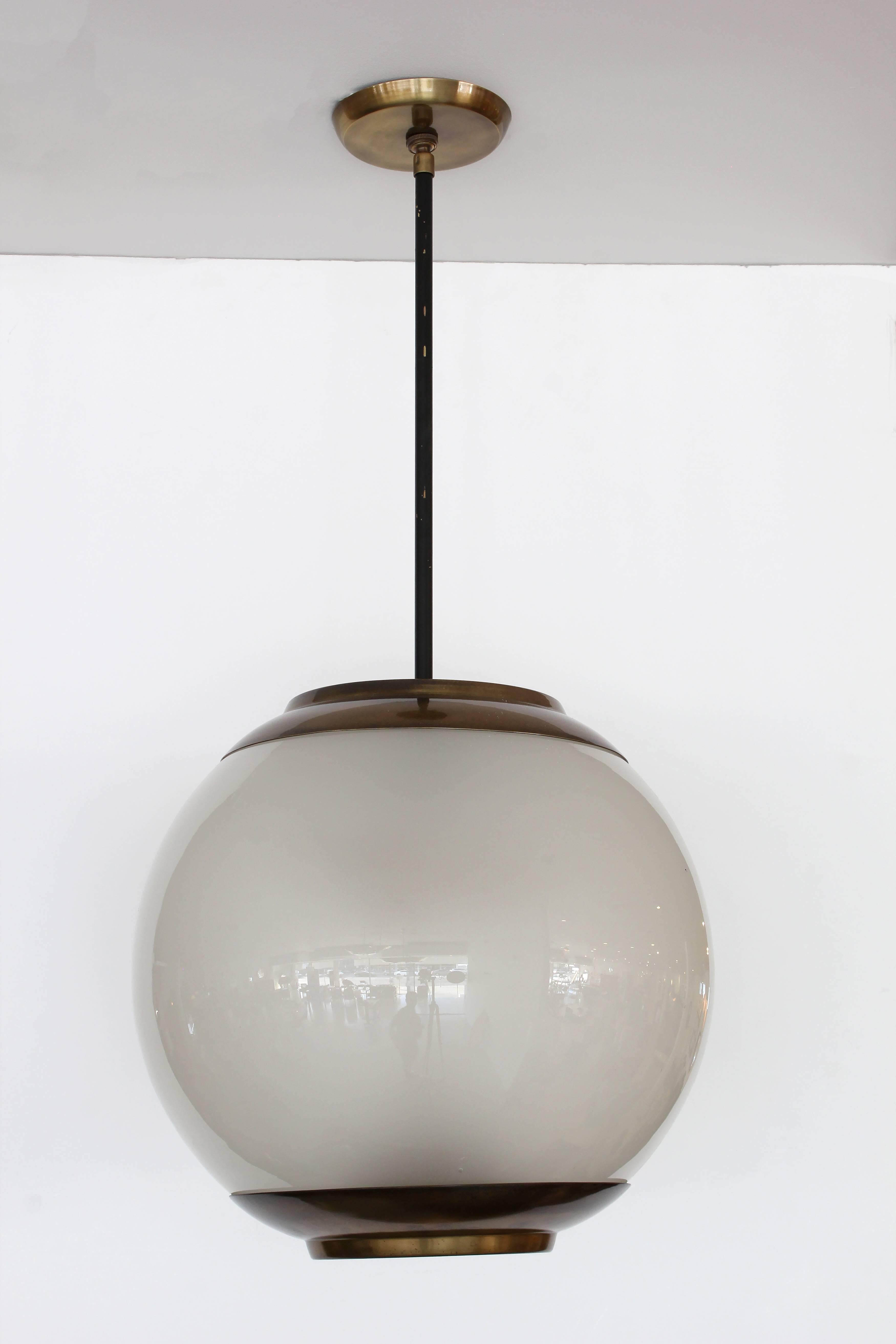 Large-scale Azucena globe pendant by Luigi Caccia Dominioni with beautiful perforated antiqued brass hardware. Globe is beautiful milky glass and large in scale. Newly rewired.