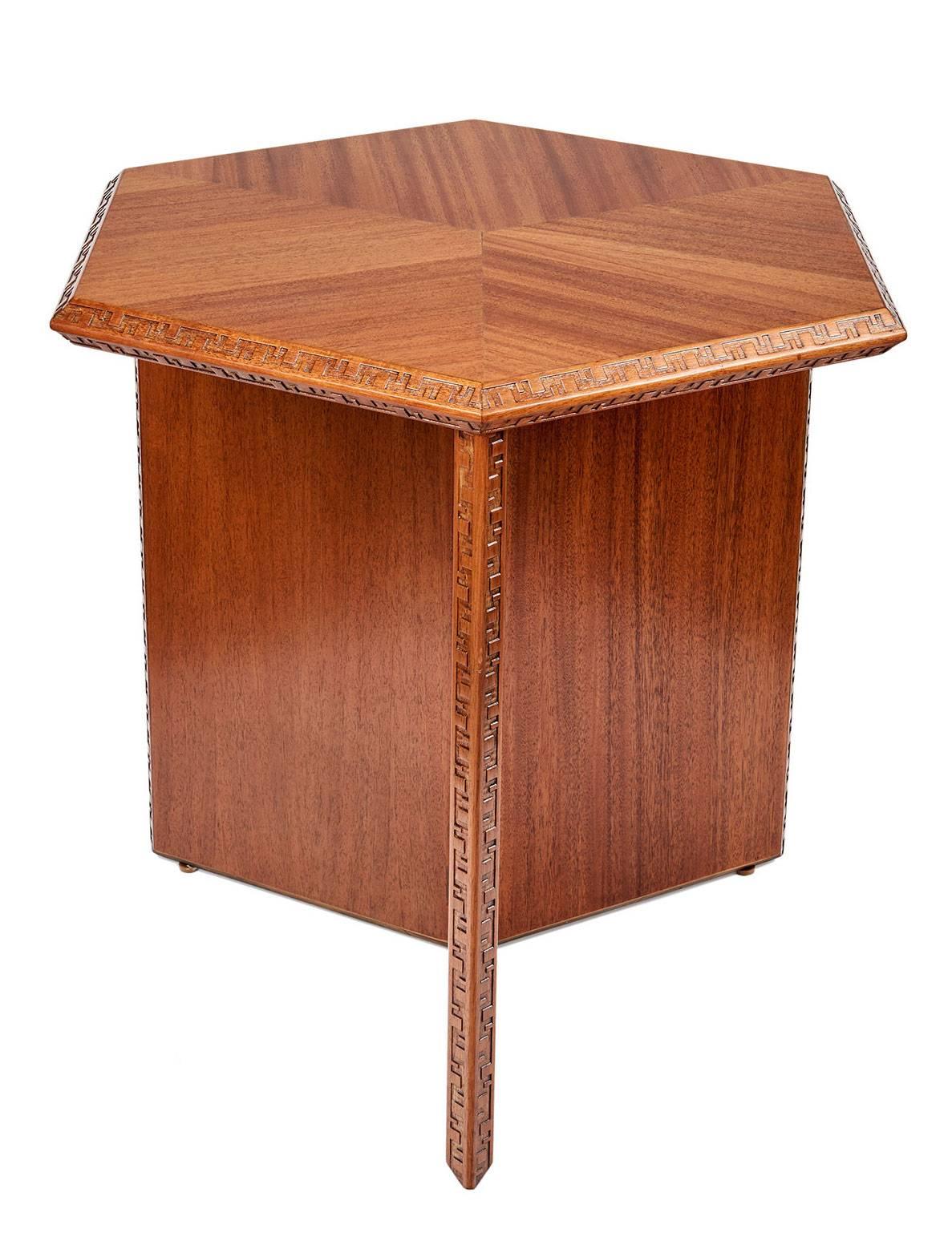 A striking, very highly architectural table designed by Frank Lloyd Wright for Henredon in the 1950s. The edges of the hexagonal top and tripartite slab base are carved with Wright's famous Taliesen 