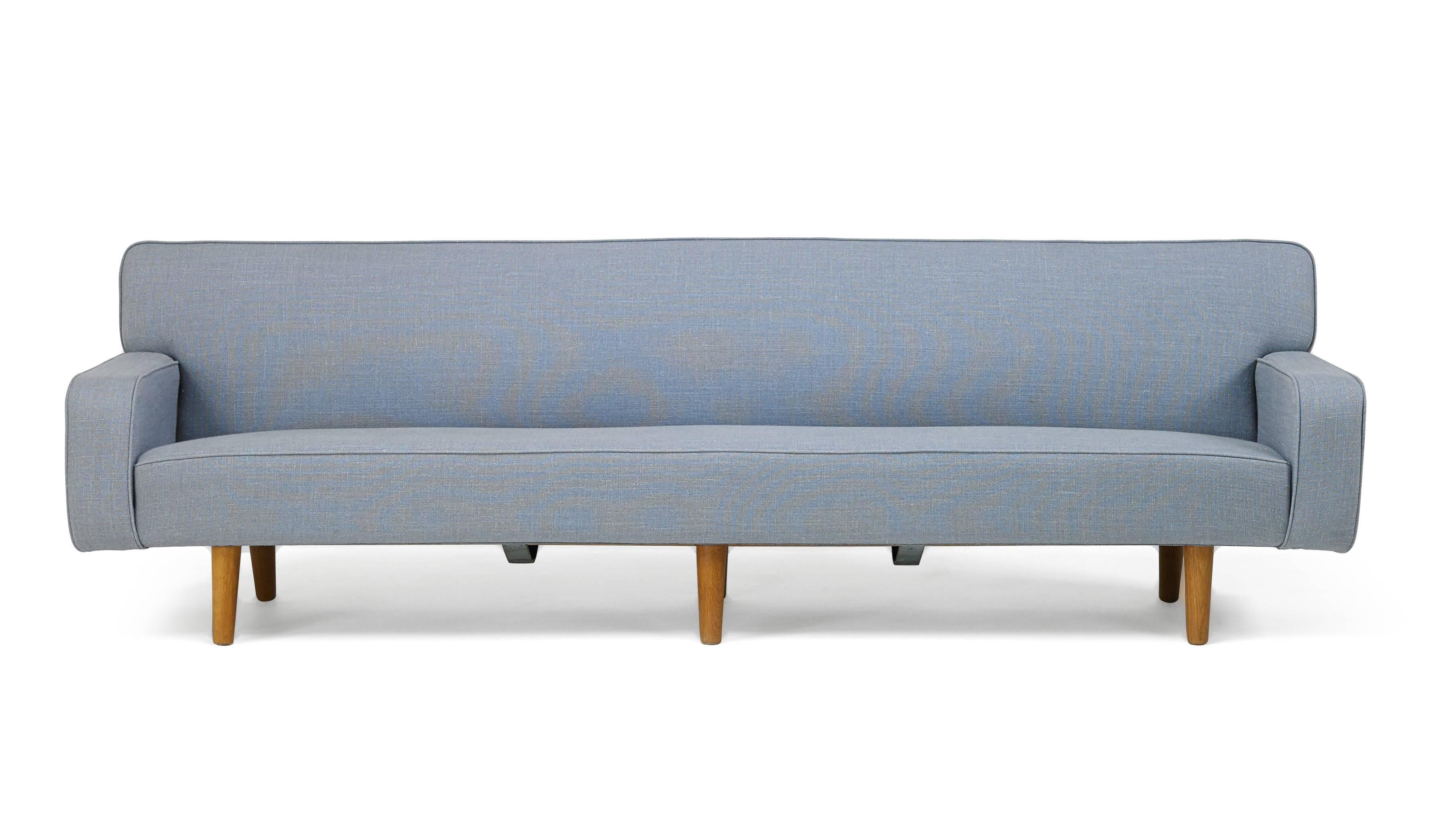 This substantial Hans Wegner sofa brings together all of the virtues of Danish design in its reconciliation of sleekness with restraint, and of jet-set modernity with the tradition of workmanship. This is the rare 99-inch-long variant of Wegner's