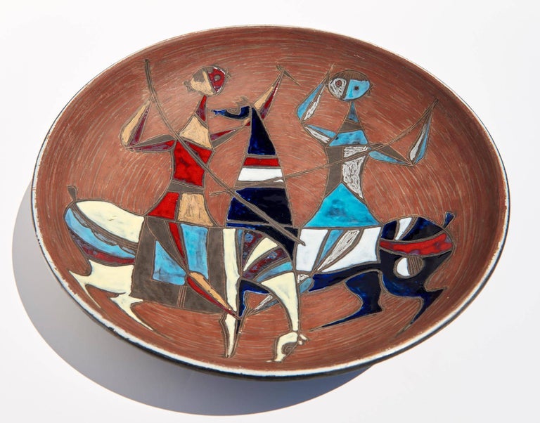 Depicting the chance encounter of two quasi-cubist knights on horseback, this large wall-plaque by the famous Florentine ceramist can also serve as a charger or centerpiece.