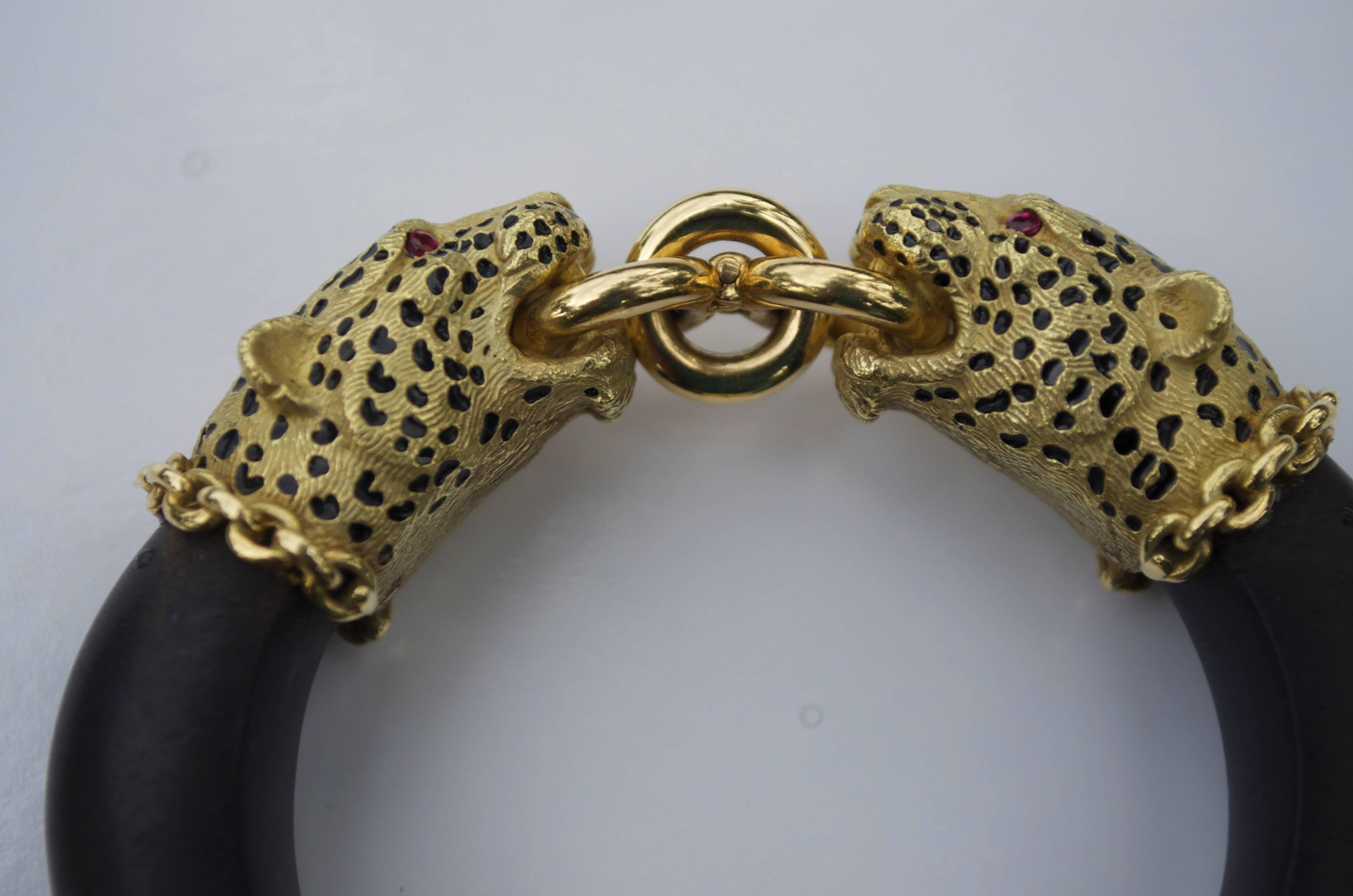 Two opposing leopards adorned with faceted ruby eyes and enameled black spots set atop a satin ebony wooden cuff. These are the outside measurements.The model's wrist is 6 3/4 