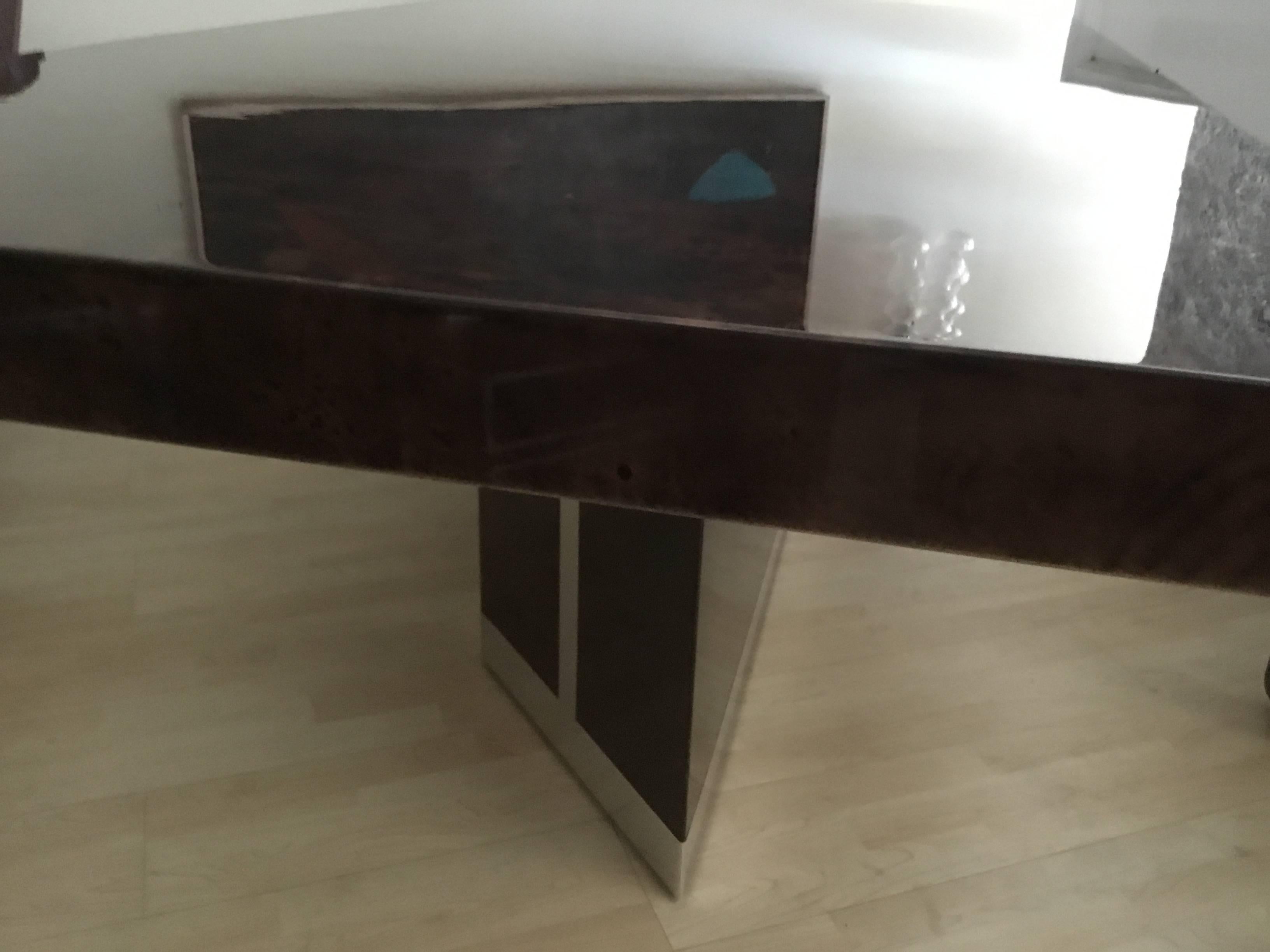 The finish is original with only one small repair. The table is a rich cognac or chocolate color. The steel banding is high polished. It is in great condition.