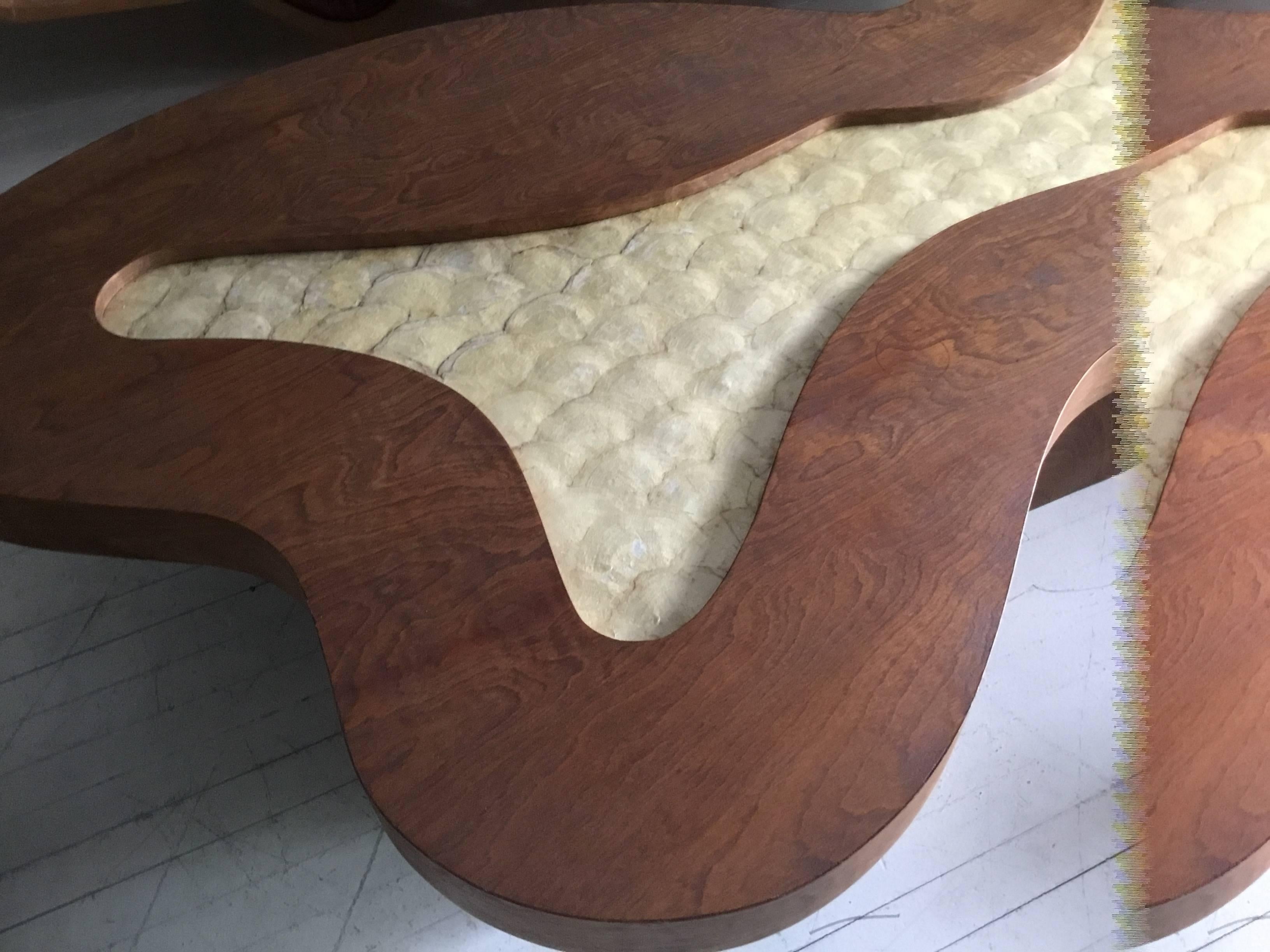 This coffee table is in the manner of Robsjohn-Gibbings. The shell top is original. The legs follow the curve of the top.