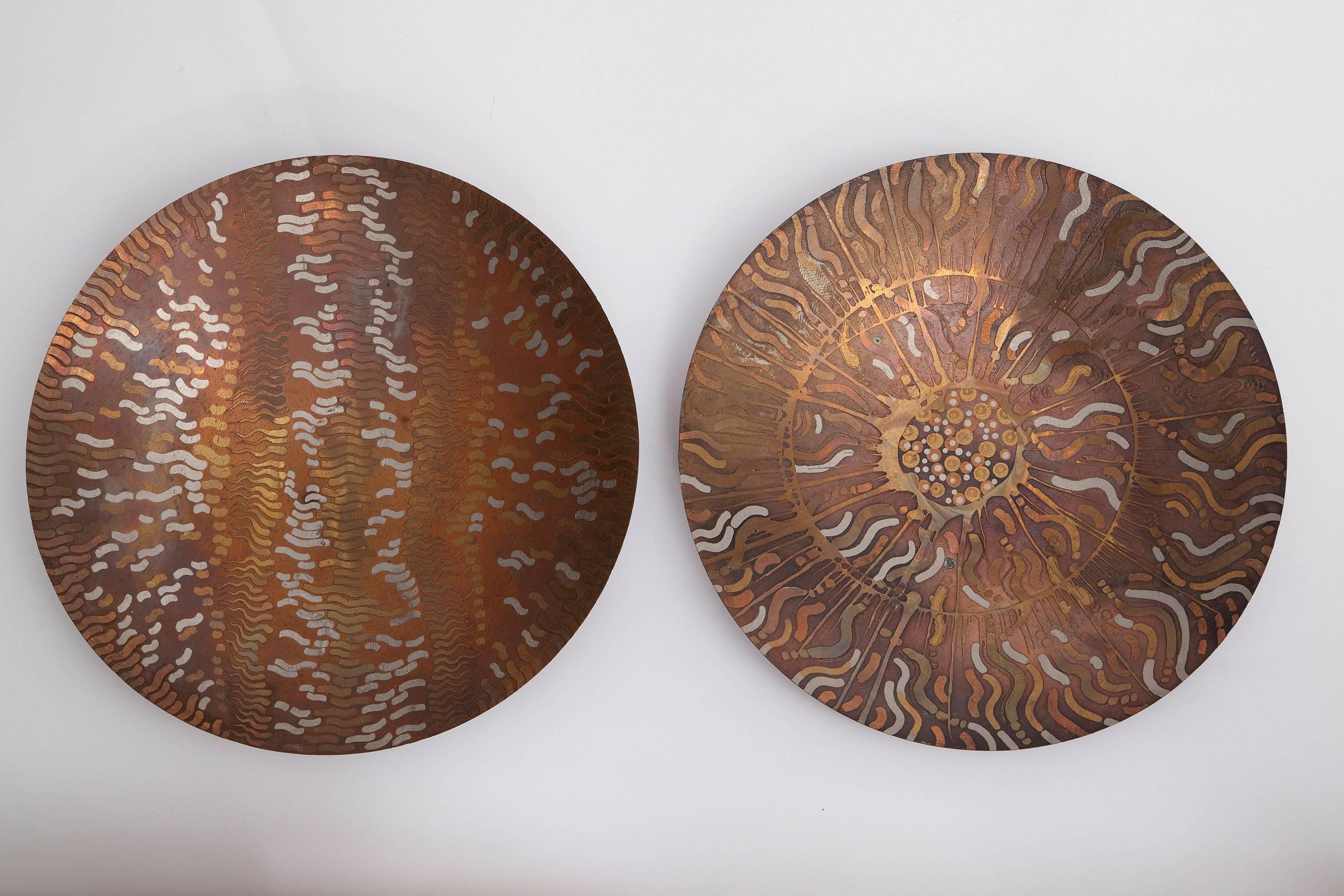 Beautifully handcrafted solid copper chargers by Lee and Naomi Peck. The 1970s and 1980s era husband and wife team were both jewelry and accessories designers. Vibrating with life, the copper charges are etched and plated with gold and silver in