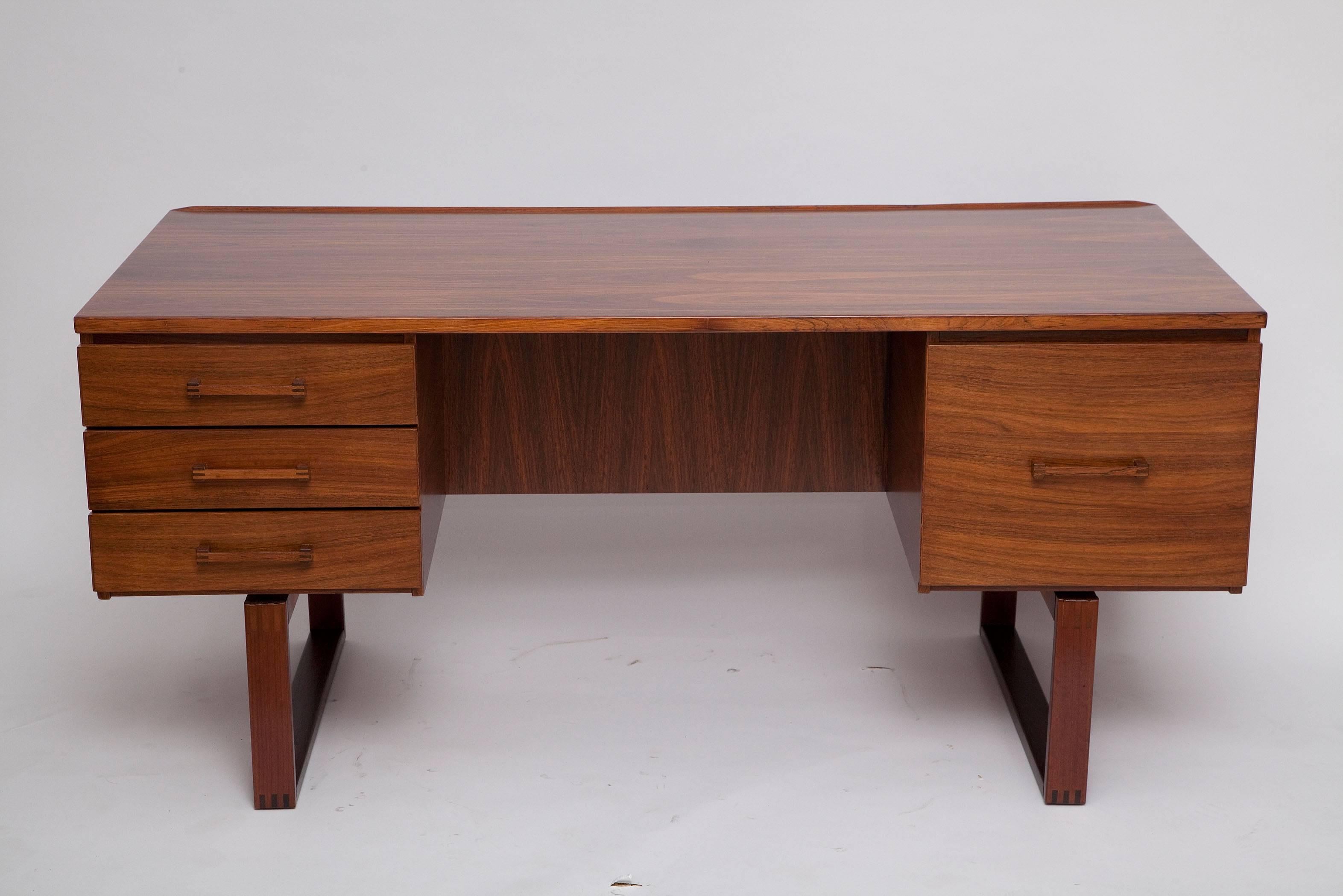 This handsome Brazilian rosewood, 1960s Danish executive desk by Henning Jensen and Torben Valeur features unique finger-jointed legs and drawer pulls. Finished back features a large storage niche for displaying collectibles or books. Kneehole