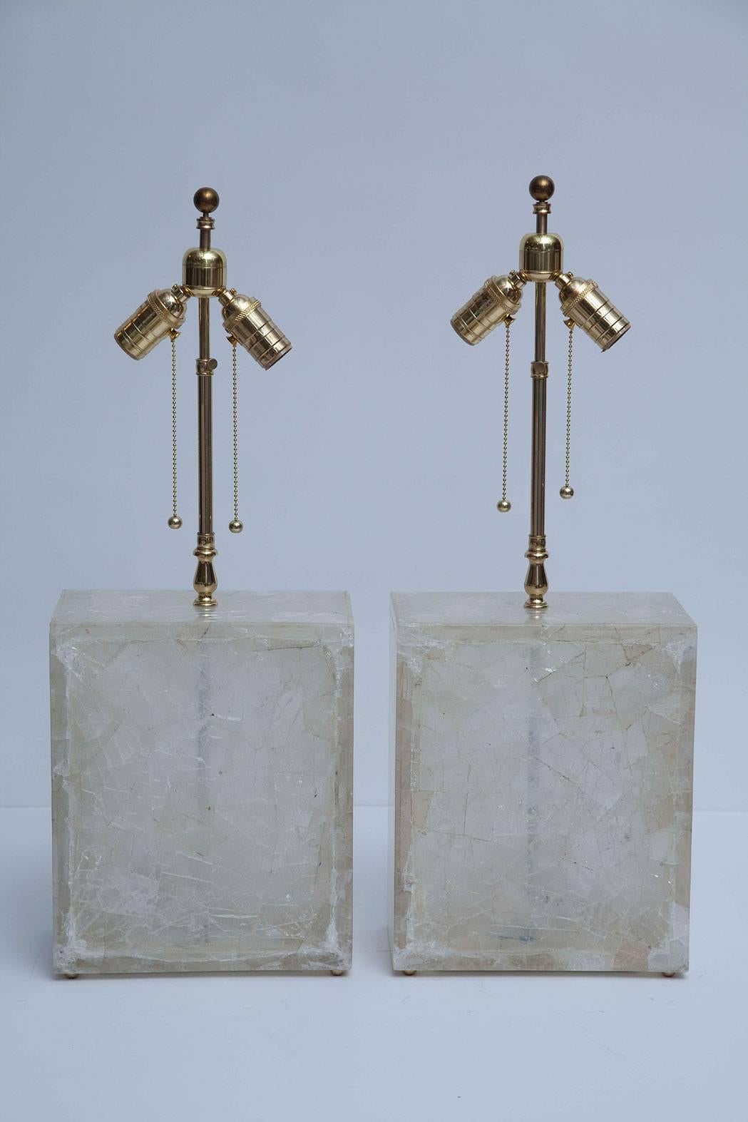 Elegant, mesmerizing table lamps composed of crackled rock crystal, backed by clear lucite. Polished solid brass hardware, with adjustable harps.