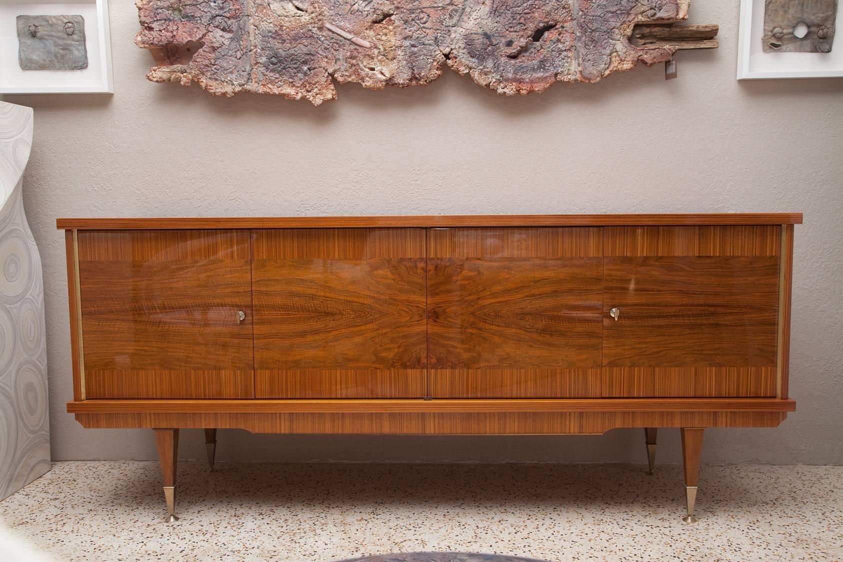 Dramatic 1960s French credenza in lacquered Zebra wood and burl walnut veneers. Sycamore interior with two wood shelves and one smoked glass shelf. Original, but un-wired interior light and original bronze-finished details and keys.
