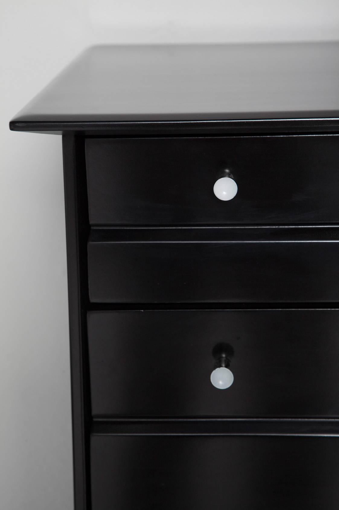 Snappy, clean-lined, five-drawer tall dresser by Heywood-Wakefield. Ebonized walnut and original, cute-as-a-button polished brass knobs with white enamel centres. Original painted interiors, ready for your lining.