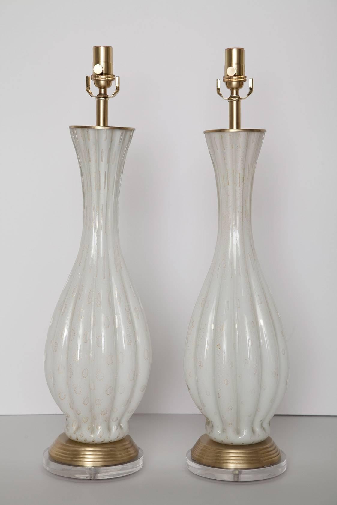 1960s handblown Murano table lamps in ribbed white glass with controlled bubbles and gold leaf. We've added a one inch acrylic base to the fully restored brushed brass hardware, and re-wired with new sockets and white fabric cord. 27 inches to top