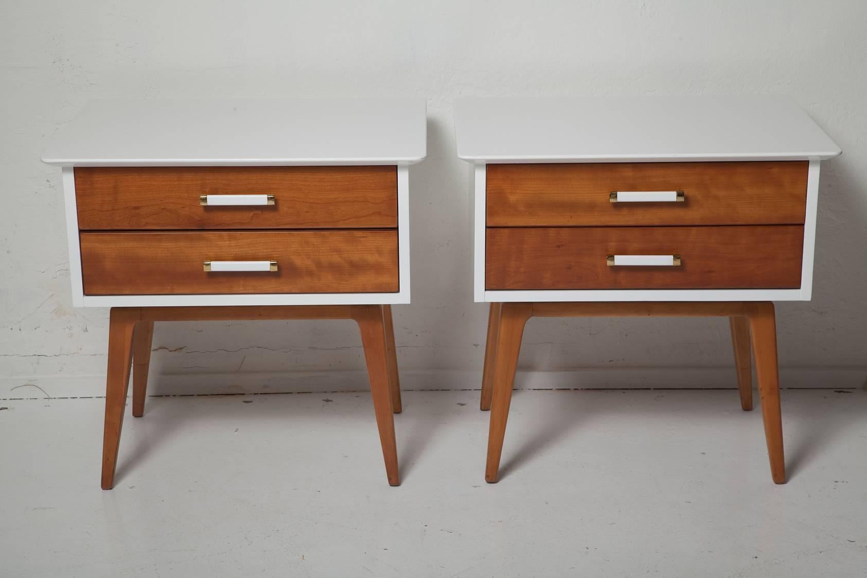 Fresh, fully restored pair of nightstands by Renzo Rutili have white lacquered bodies with contrasting cherrywood drawer fronts, legs, and handles with polished brass trim, circa 1955.