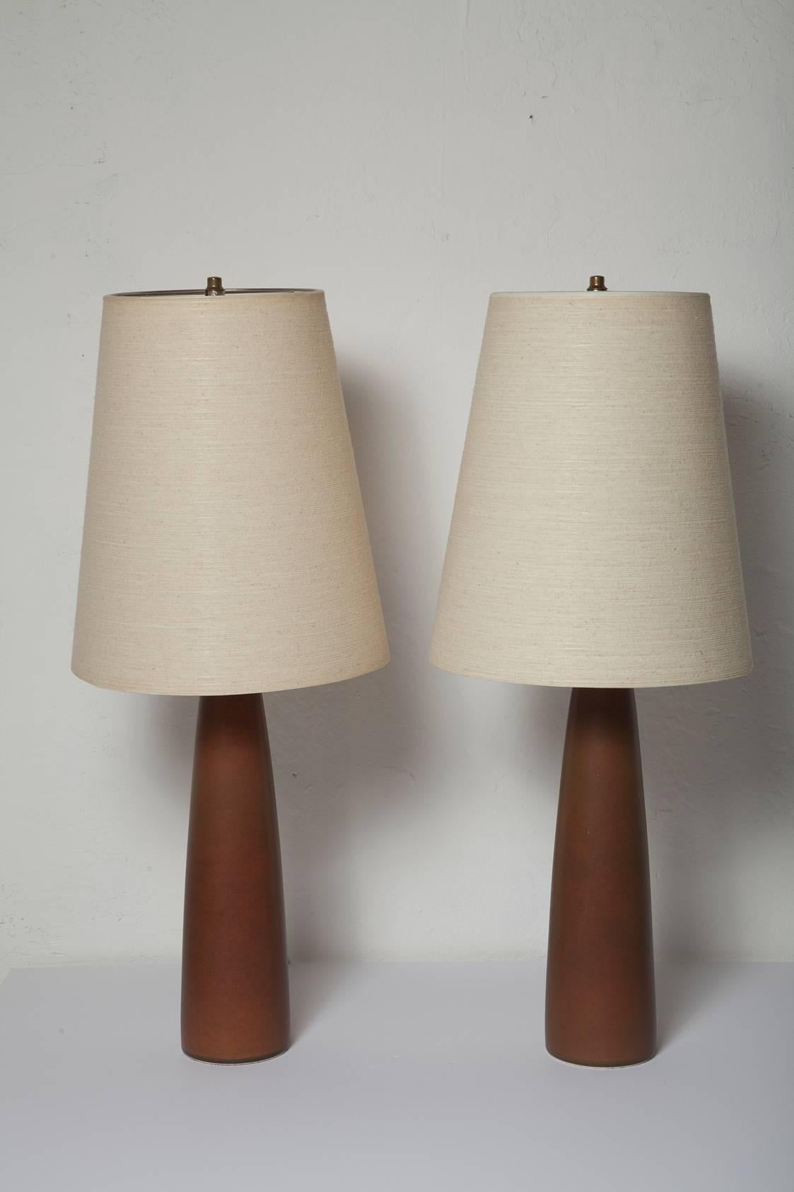 Tall, handsome pair of lamps by Lotte and Gunnar Bostlund with warm brown ceramic bases and original jute wrapped fiberglass shades. Photos show the magical effect light gives to the textured shades with both high and low wattage.