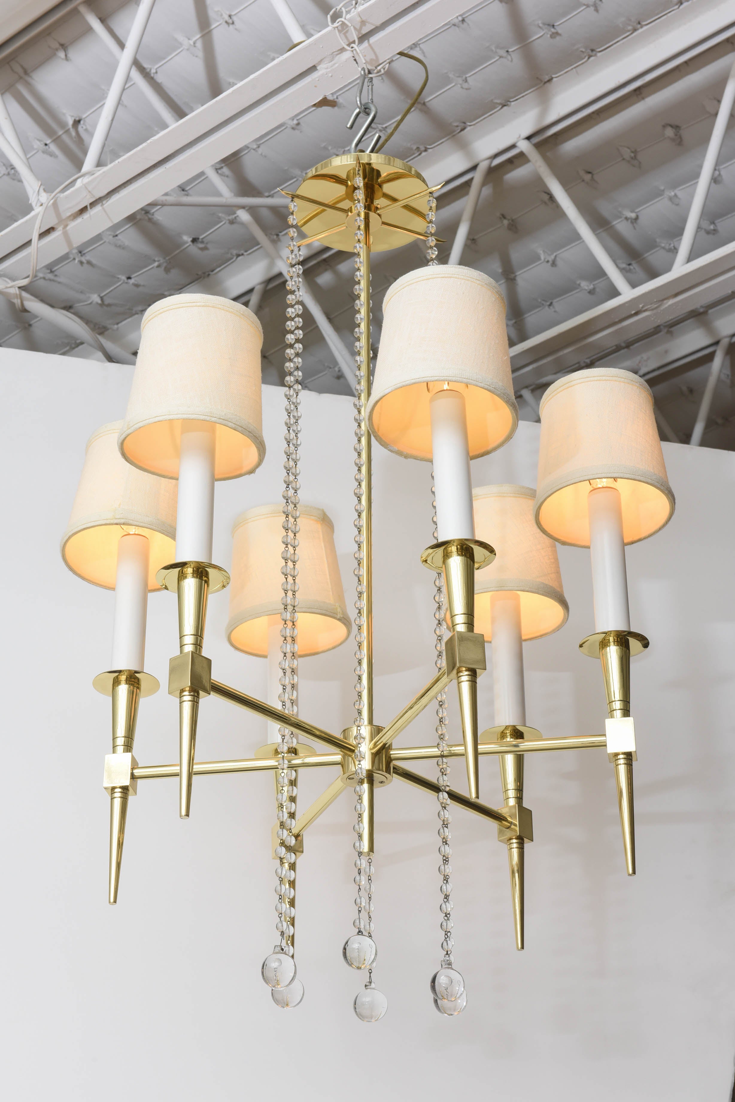 A light both commanding and delicate! Solid brass and glass beaded six-light chandelier by Tommi Parzinger, circa 1955. Professionally polished and re-wired. Linen shades.