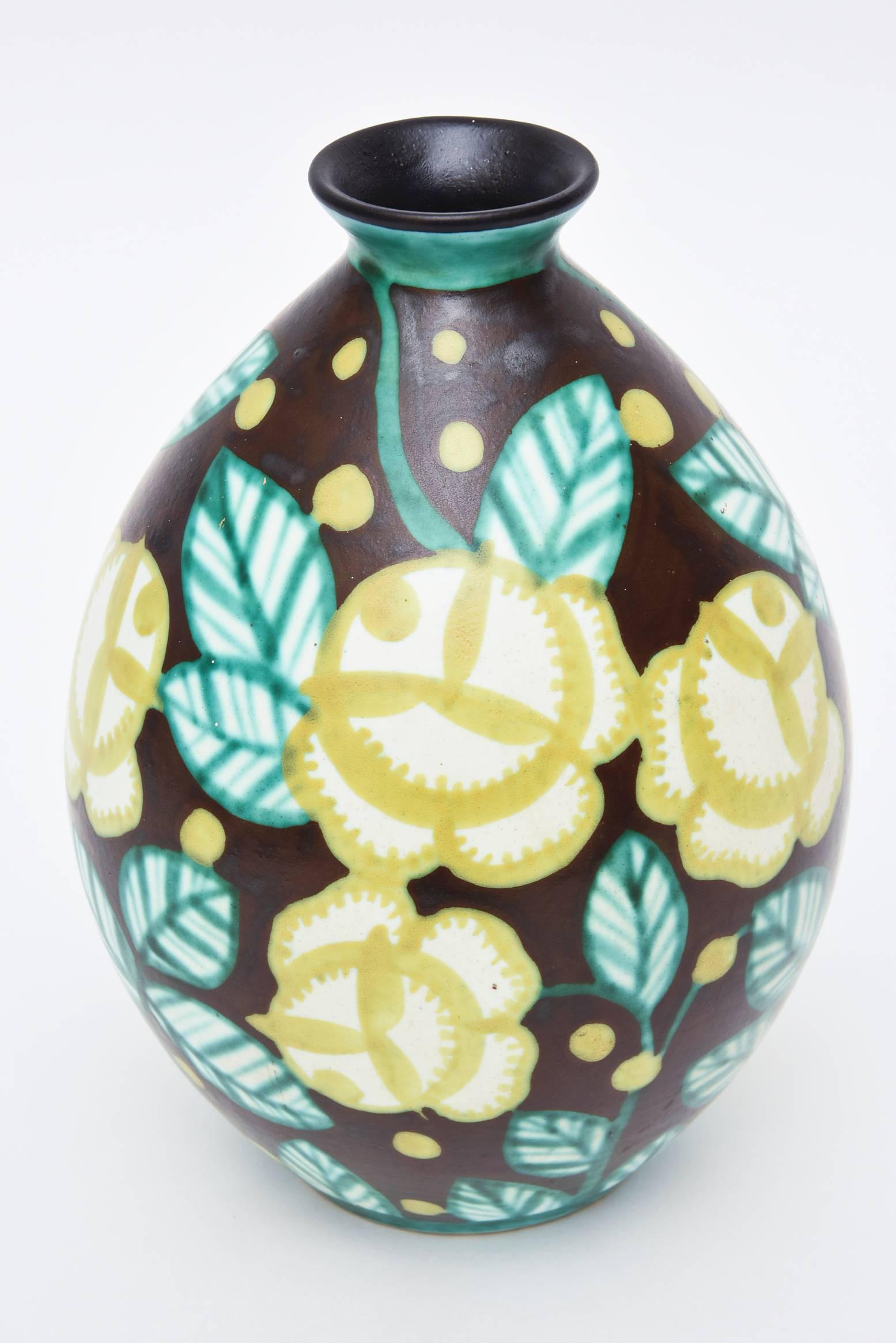 This ceramic vase by Keramis is unusual in its pattern and color format.
The foliage is set against a dark brown with chartreuse yellow and teal green leaf.
All of the numbers and hallmarks are on the bottom.