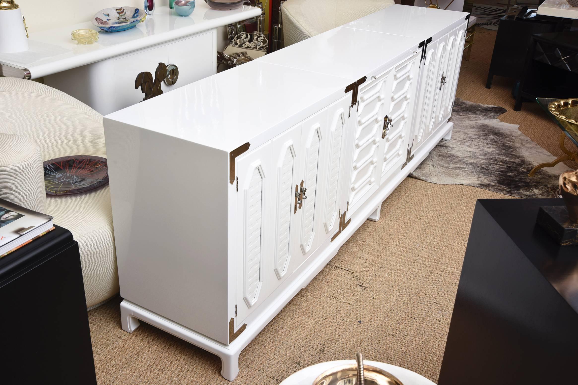 This 1960s vintage white lacquered wood textural three part cabinet or buffet sits on a long base. It has the original  fabulous hardware that has been nickeled silver over the brass. The dimensional wood relief doors are in different patterns on
