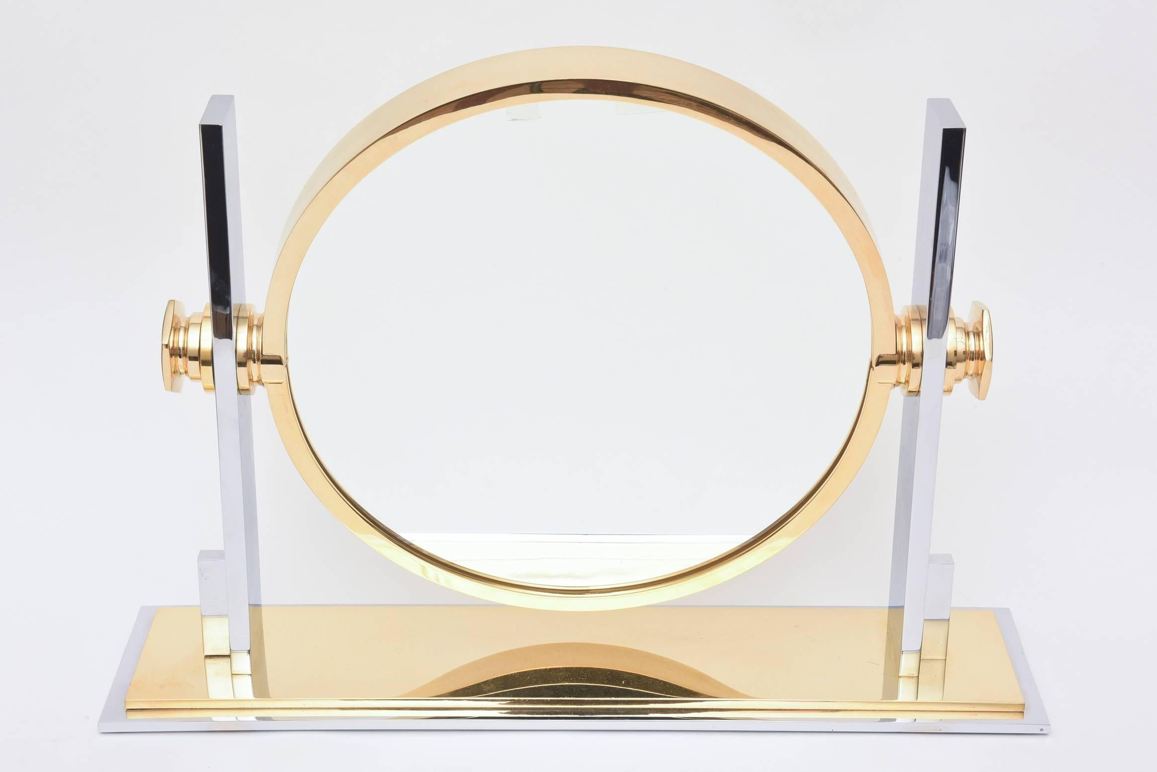 This 24-karat gold-plated over chrome and chrome-plated brass vanity mirror has the double sides, one for magnification and the other normal. The richness of the mixed metals add depth.
It is Karl Springer. The weight and modern design transcends