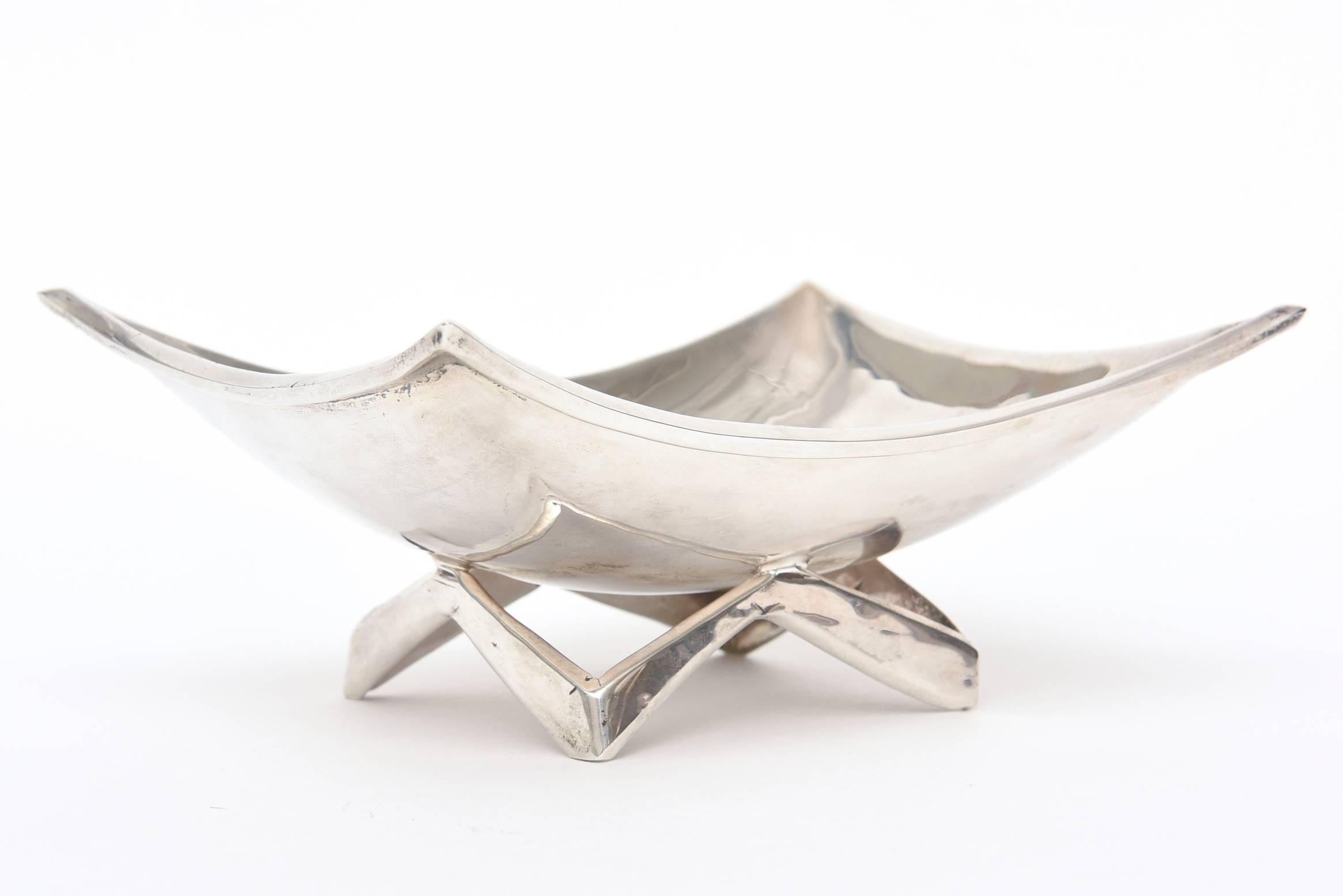 This lovely small hallmarked sterling silver modernist bowl is signed.
The shape is sculptural and the architectural sterling base acts as a pedestal.
It has nice weight to it.
It is marked 925 JLR 0.92. It is by one of the Mexican silversmith's