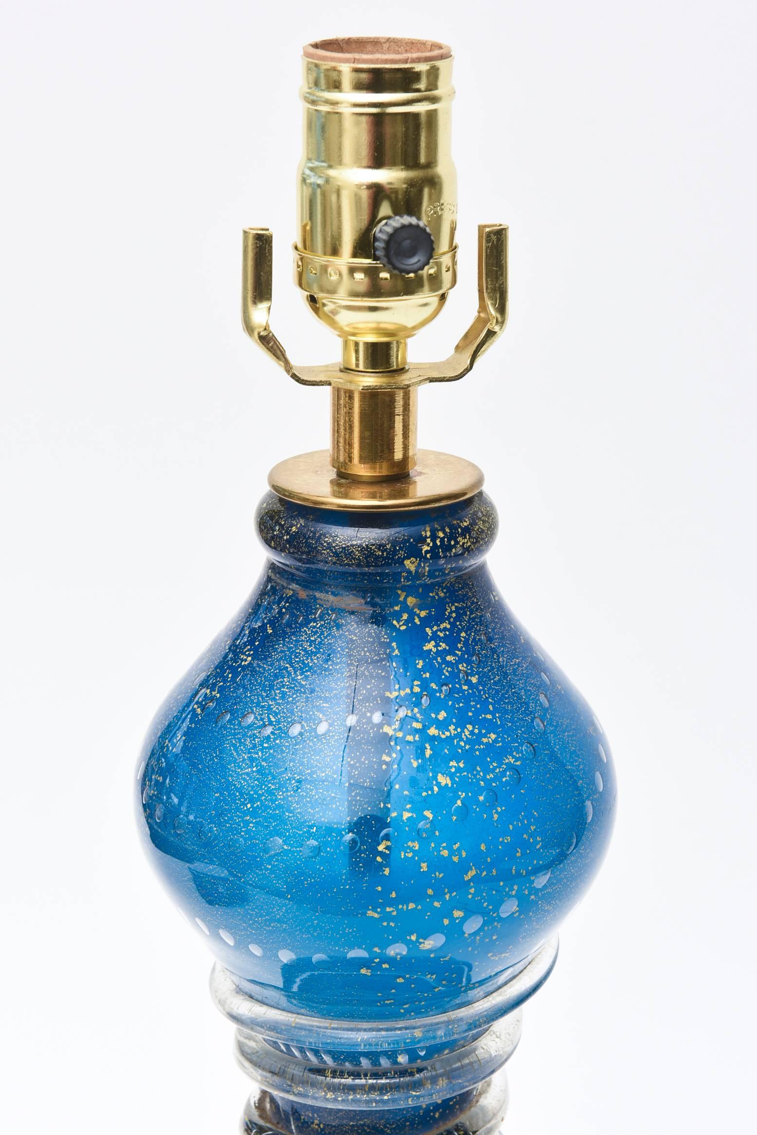The luscious color of sapphire blue rings in richness and attention.
This lovely and beautiful desk/ table lamp has swirls of applied concentric glass on the center portion with interior bubbles and a great abundance of gold aventurine throughout